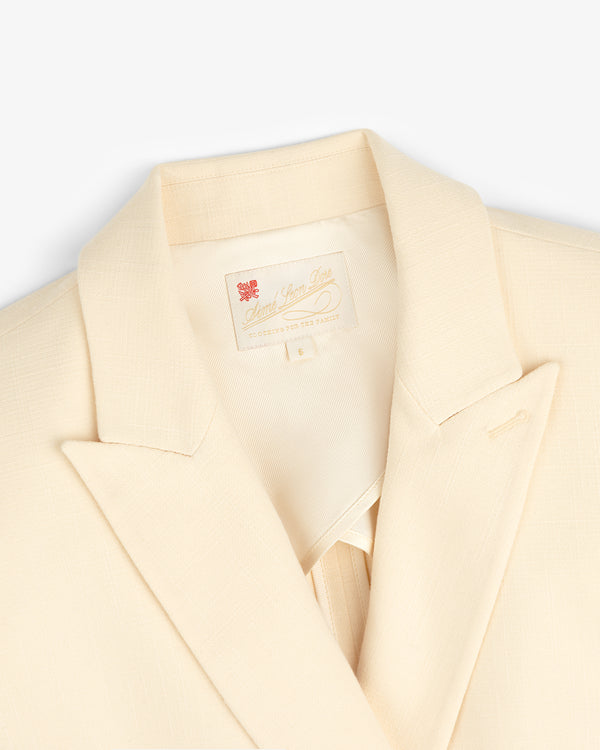 Close-up of the Double-Breasted Unconstructed Blazer in cream with notched lapel and sewn-in collar label.