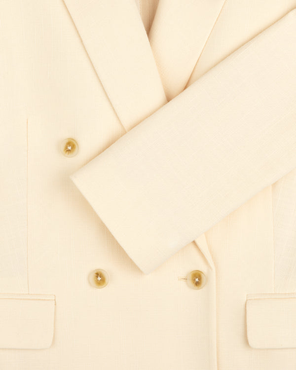 Close-up of the Double-Breasted Unconstructed Blazer in cream with four tan buttons, two front pockets, and a folded sleeve.
