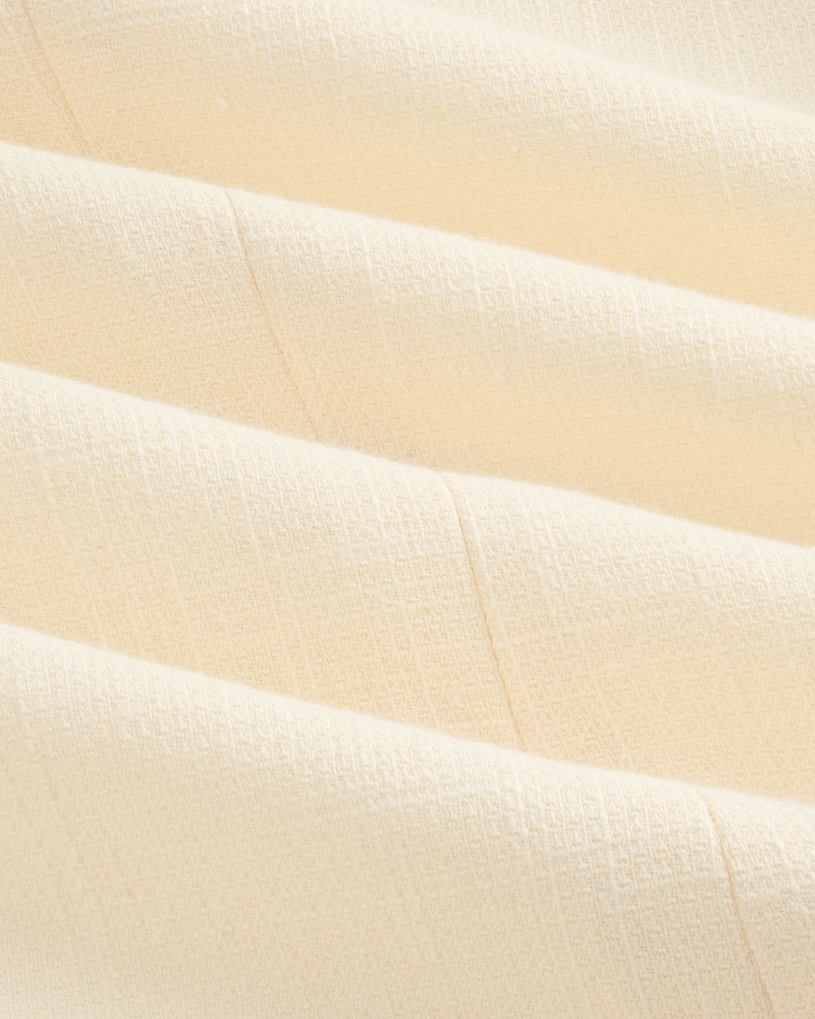 Close-up of cream-colored textured fabric with subtle grid pattern on a Double-Breasted Unconstructed Blazer.