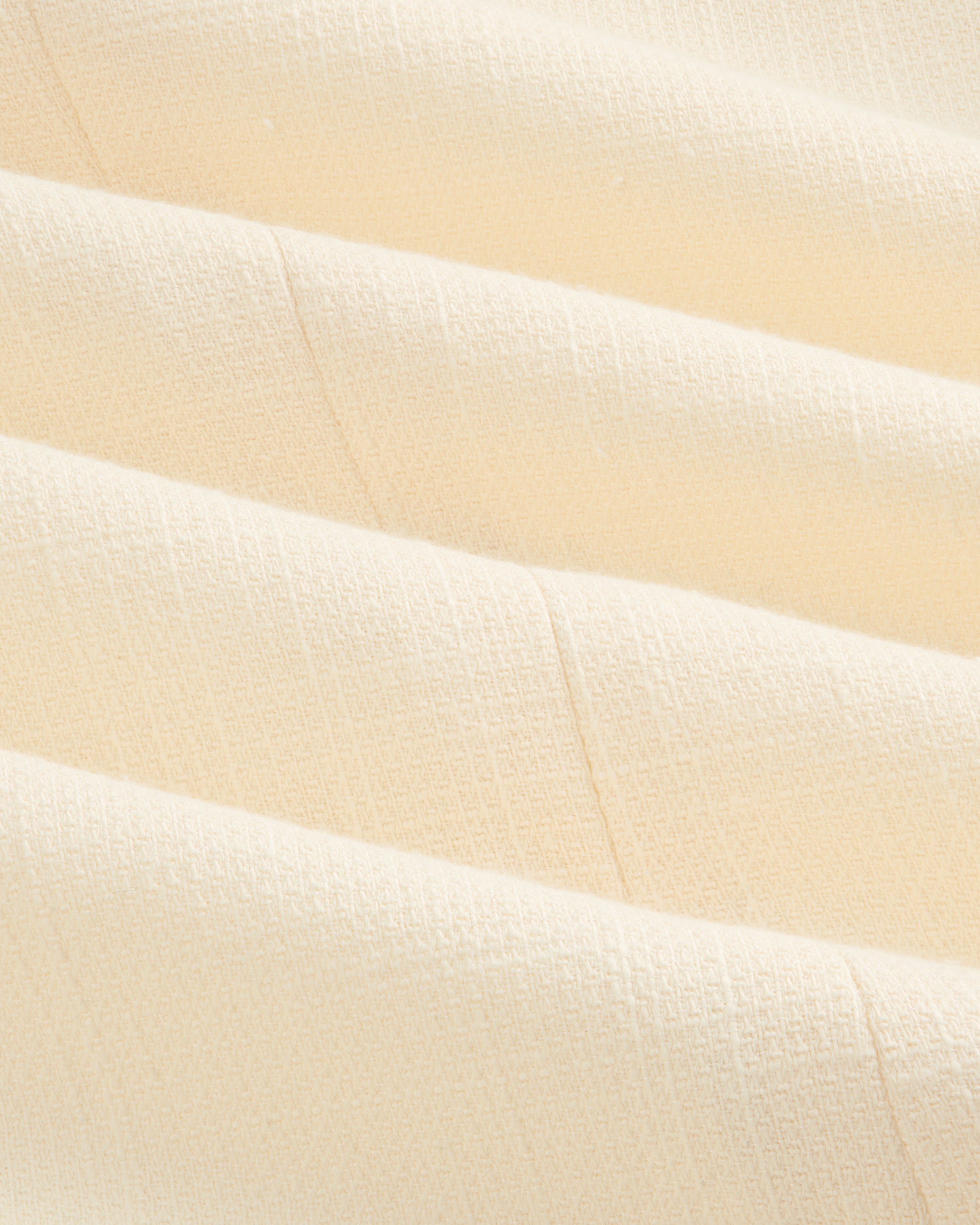 Close-up of cream-colored textured fabric with subtle grid pattern on a Double-Breasted Unconstructed Blazer.