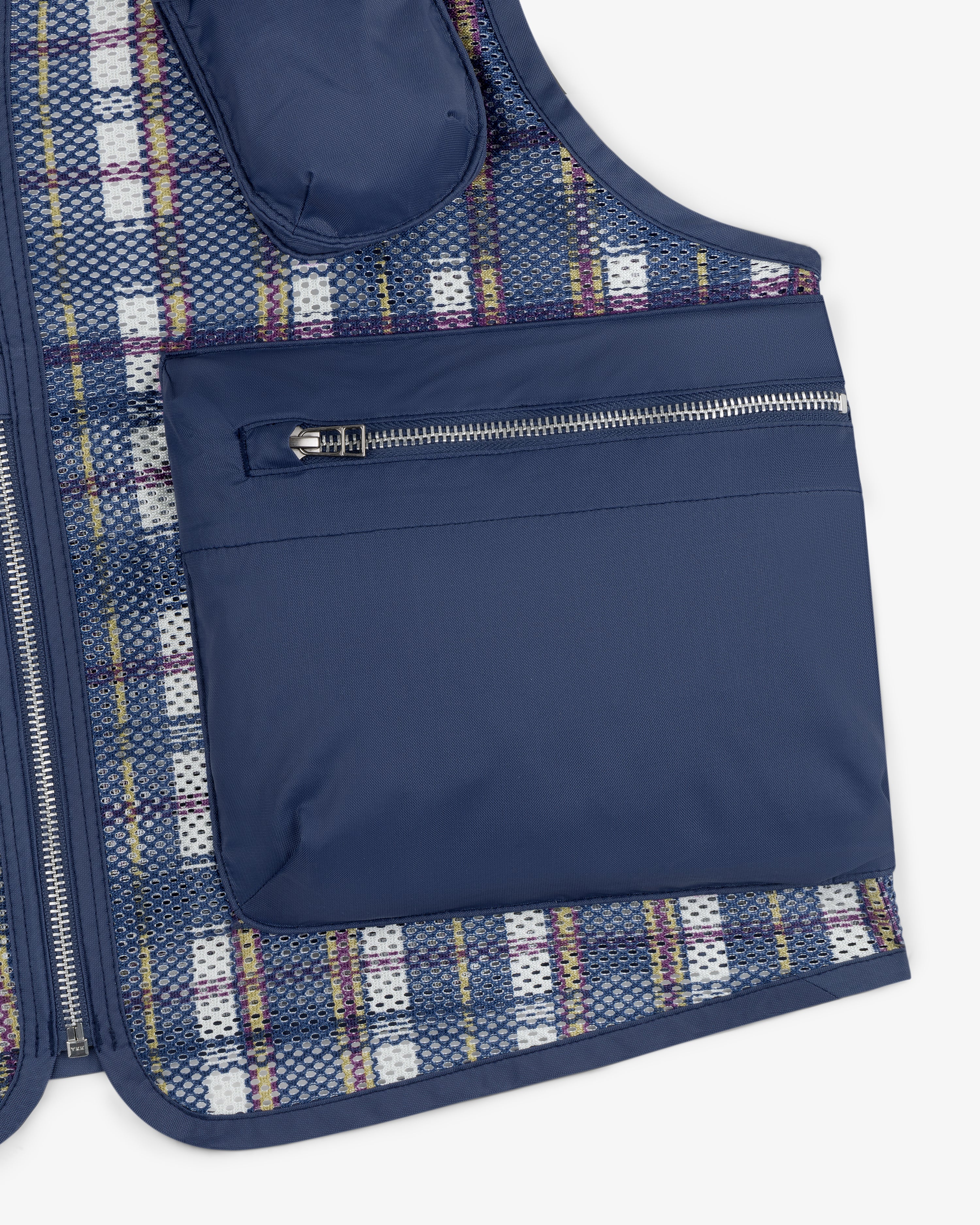 Close-up of the Nylon Madras Utility Vest with a blue finish, large zippered pocket, and plaid mesh lining underneath.