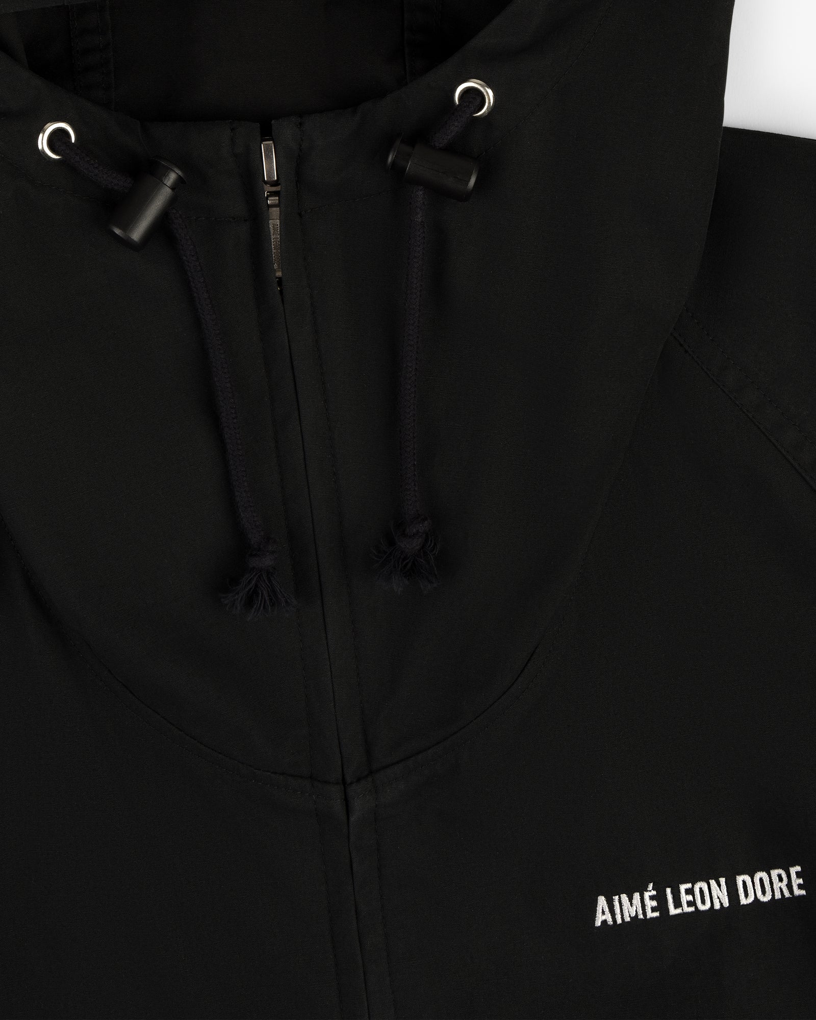 Close-up of the Micro Logo Lightweight Jacket, a black zip hoodie with AIMÉ LEON DORE embroidered in white on the chest.