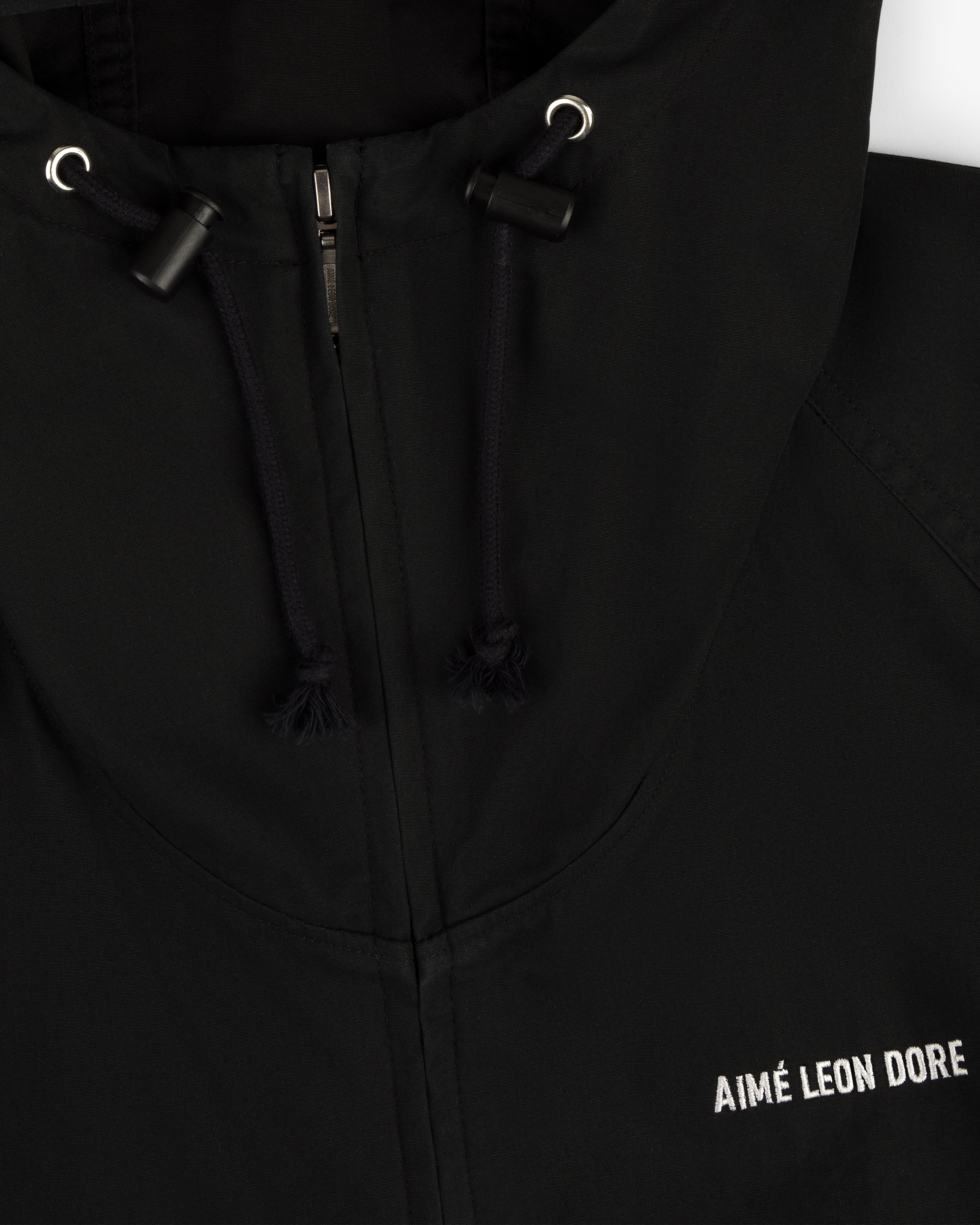 Close-up of the Micro Logo Lightweight Jacket, a black zip hoodie with AIMÉ LEON DORE embroidered in white on the chest.