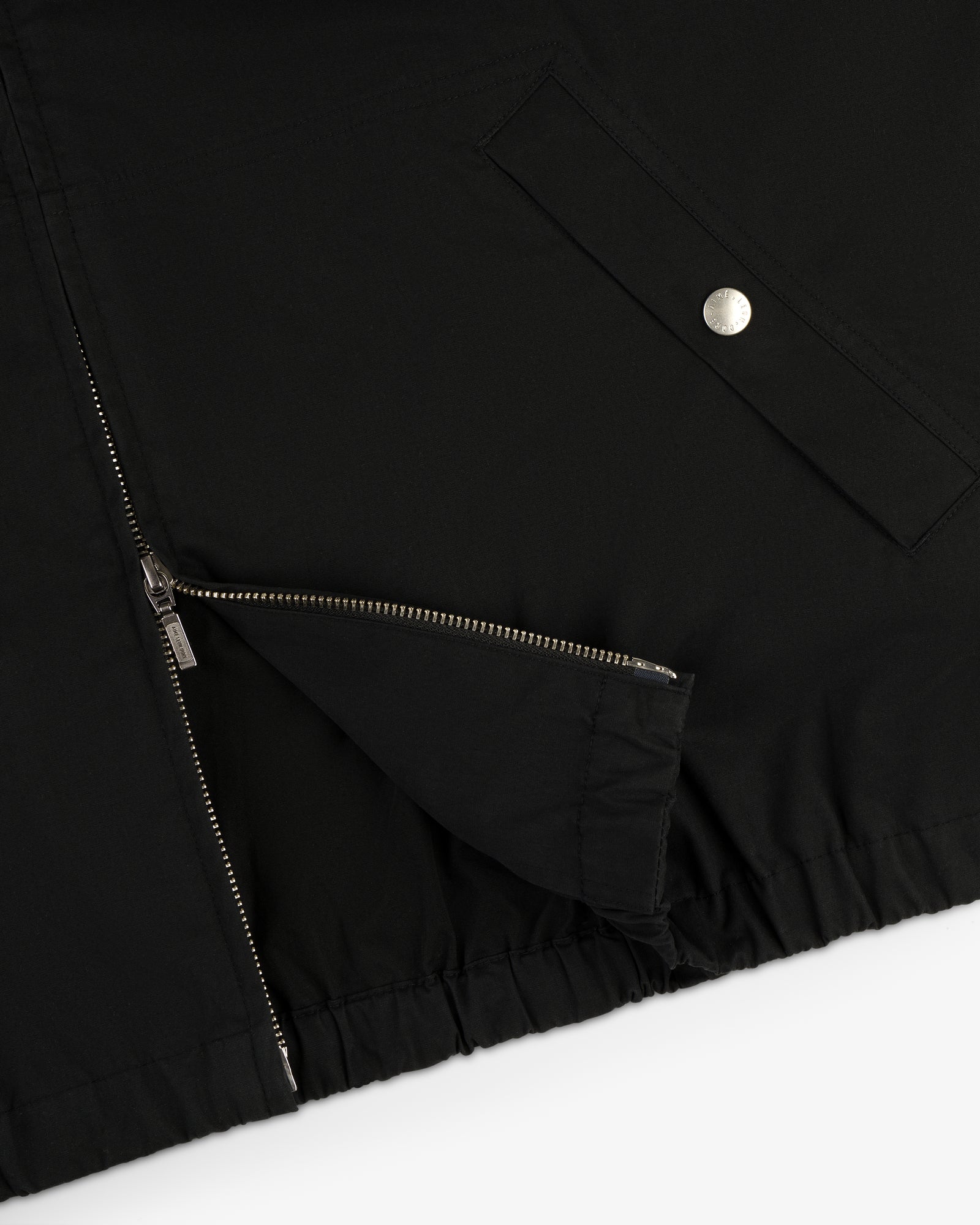 Close-up of the Micro Logo Lightweight Jacket in black, featuring a zippered opening and a silver snap-button pocket.