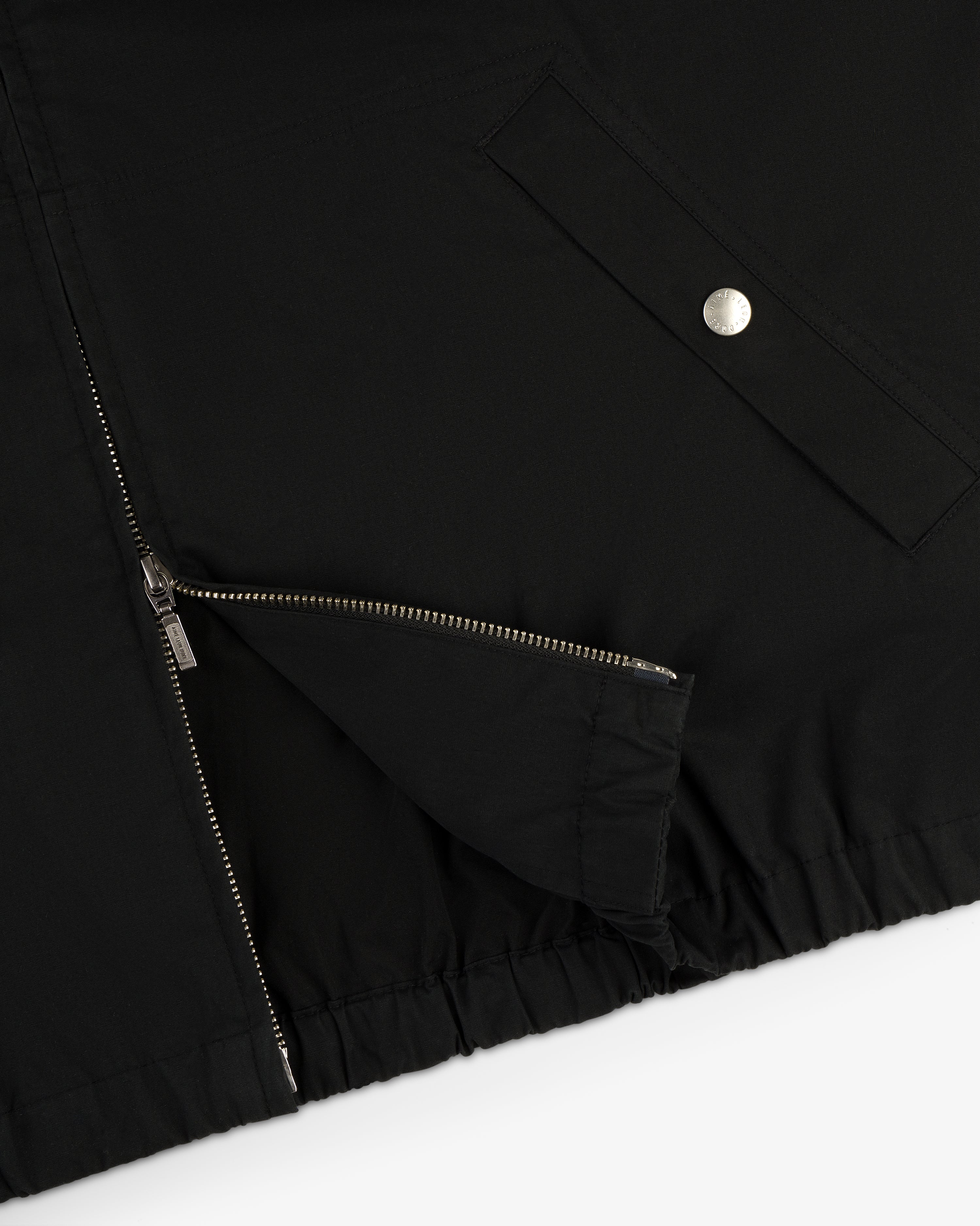 Close-up of the Micro Logo Lightweight Jacket in black, featuring a zippered opening and a silver snap-button pocket.
