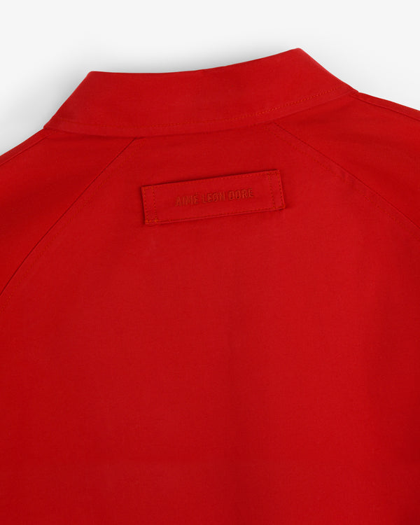 Close-up of the back of a red Crest Casual Jacket with a small rectangular label reading AIMÉ LEON DORE.