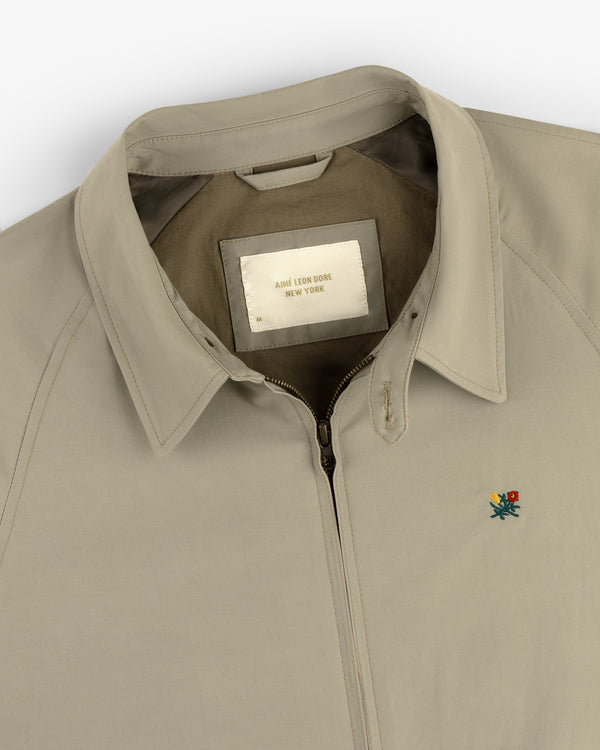 Beige Crest Casual Jacket with collar, zip-up front, small floral embroidery, and inside "Aimé Leon Dore New York" label.