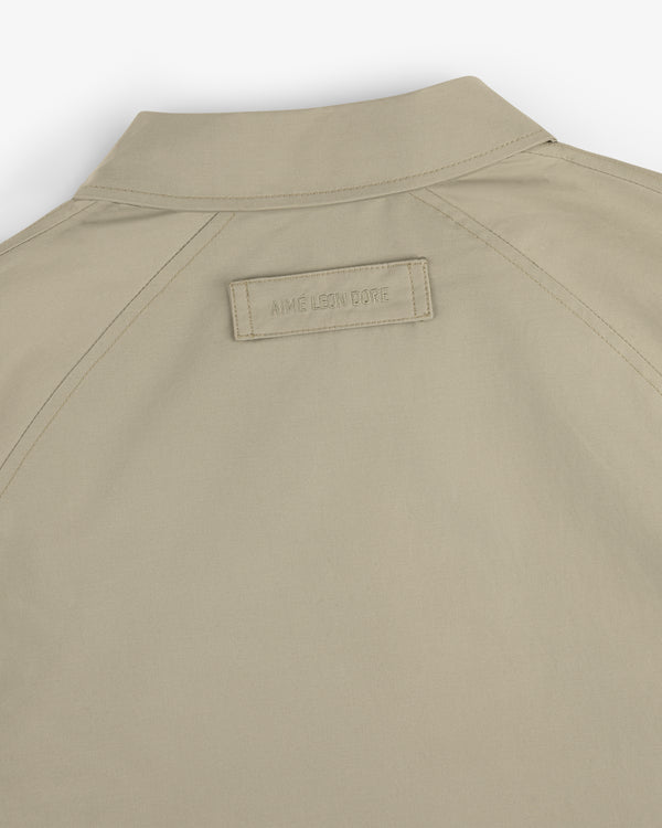 Beige Crest Casual Jacket with a small rectangular AIMÉ LEON DORE patch beneath the collar on the back.