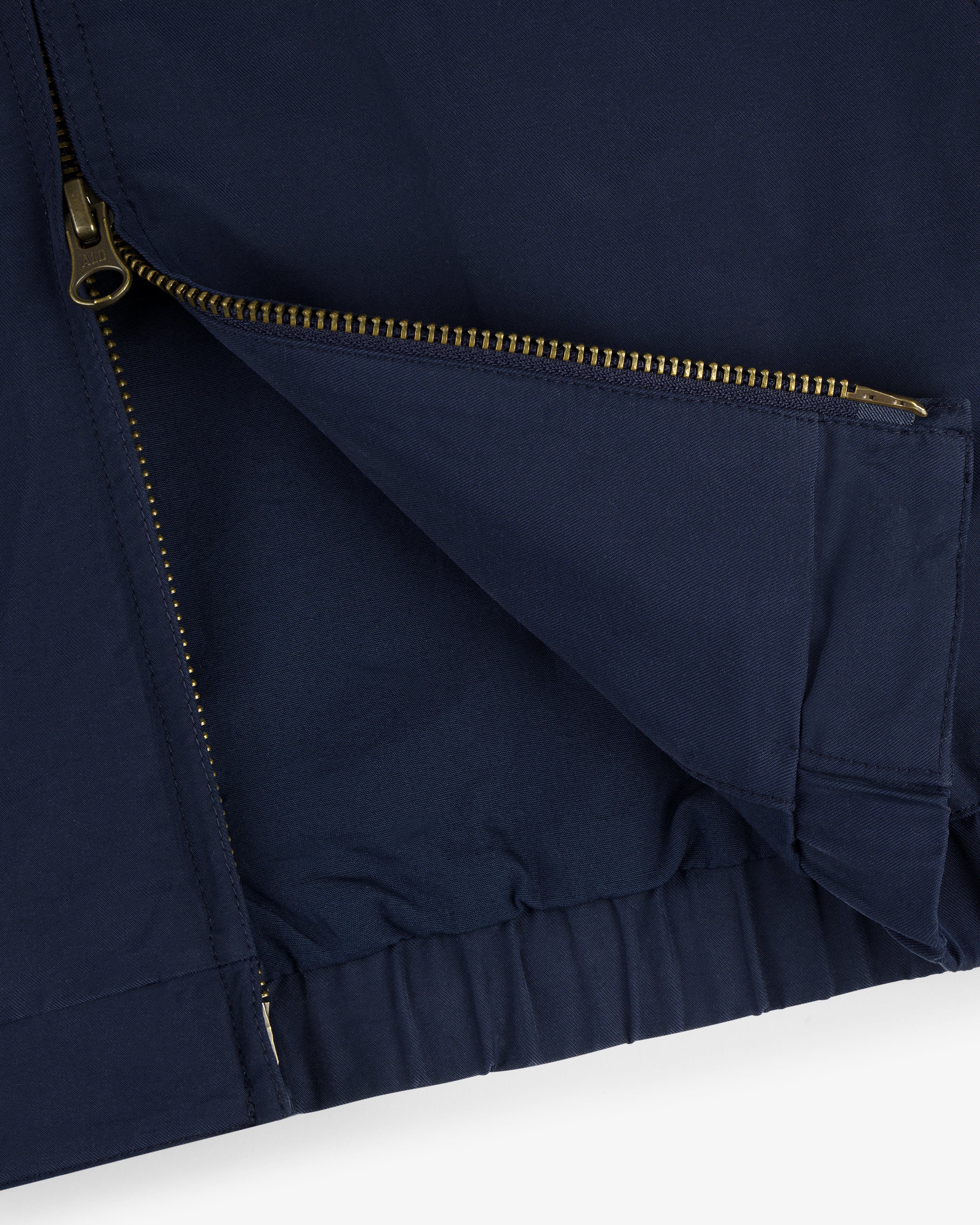 Close-up of the Crest Casual Jacket in navy with a partially open gold zipper and visible fabric folds.