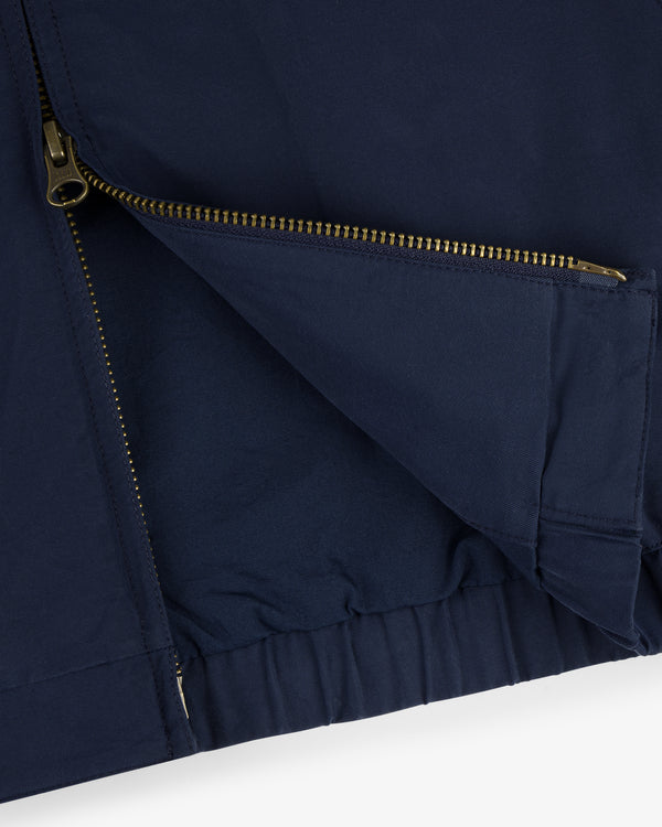 Close-up of the Crest Casual Jacket in navy with a partially open gold zipper and visible fabric folds.