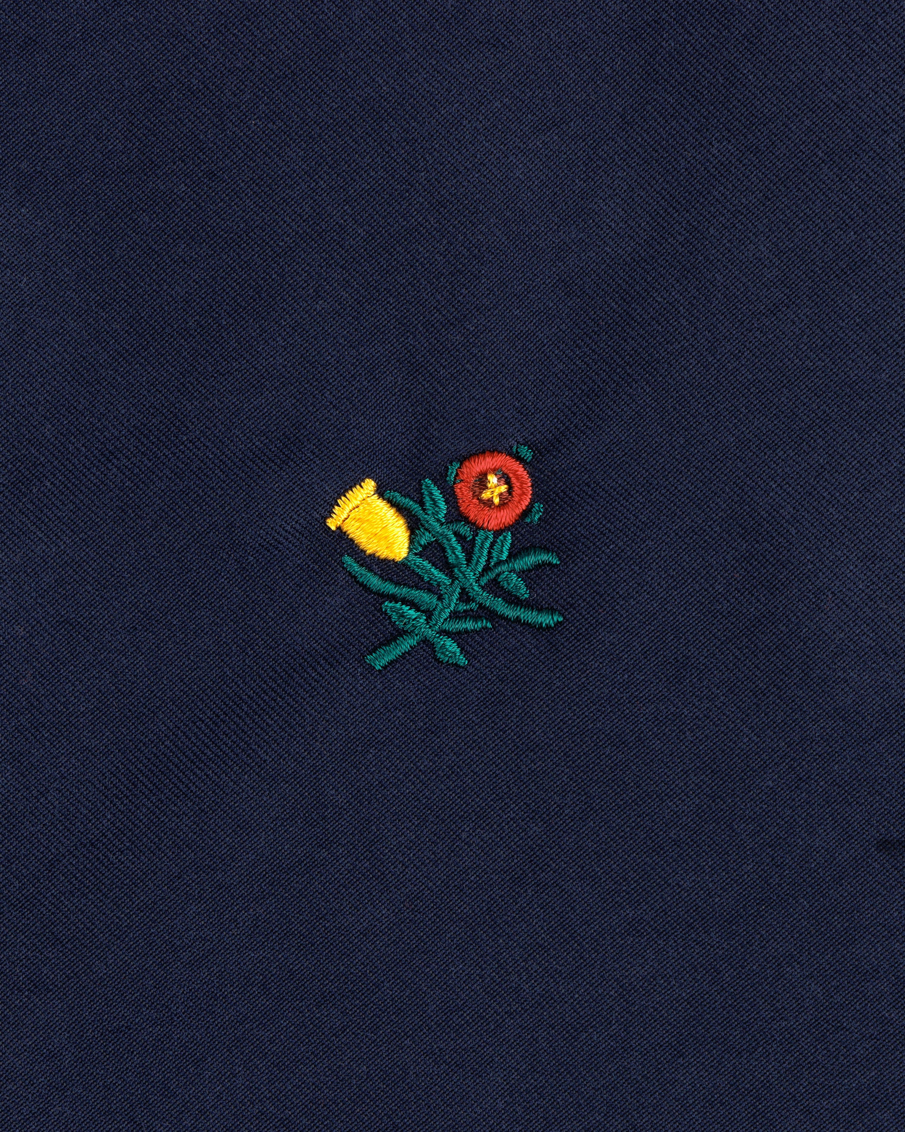 Embroidered yellow and red flowers with green stems adorn the Crest Casual Jacket's dark blue fabric.