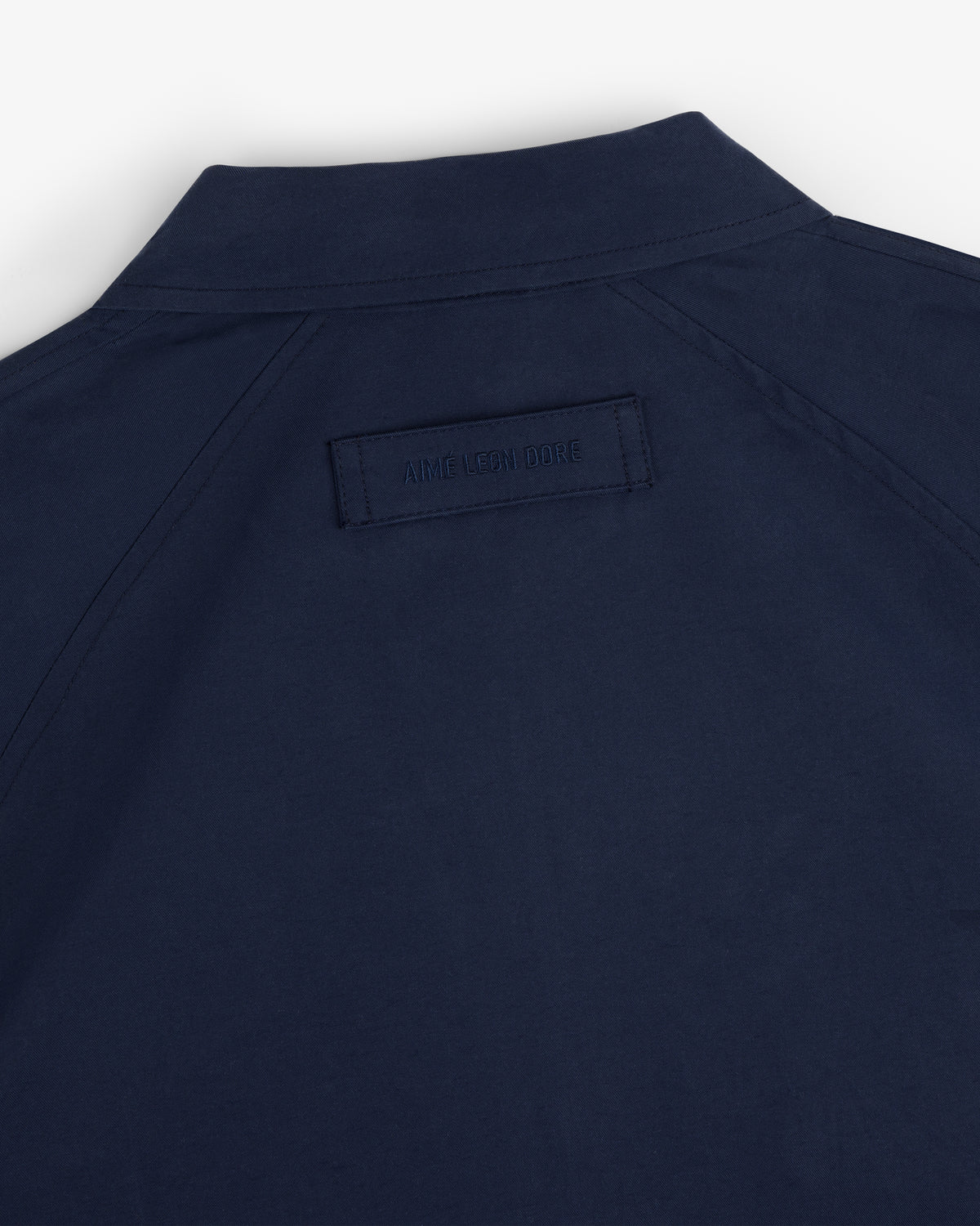 Navy Crest Casual Jacket with a collar and rectangular AIME LEON DORE label stitched on the upper back.