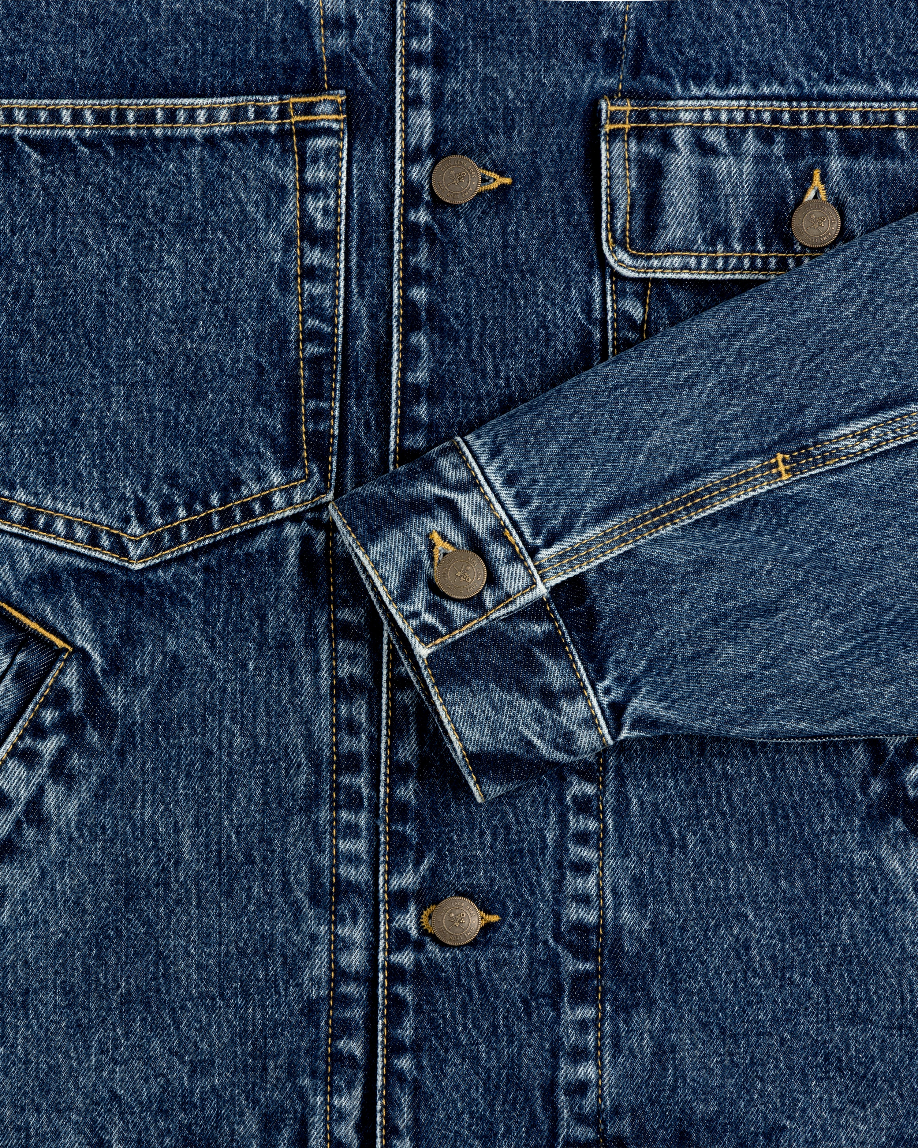 Close-up of Denim Trucker Jacket with front pockets, visible buttons, and detailed stitching.