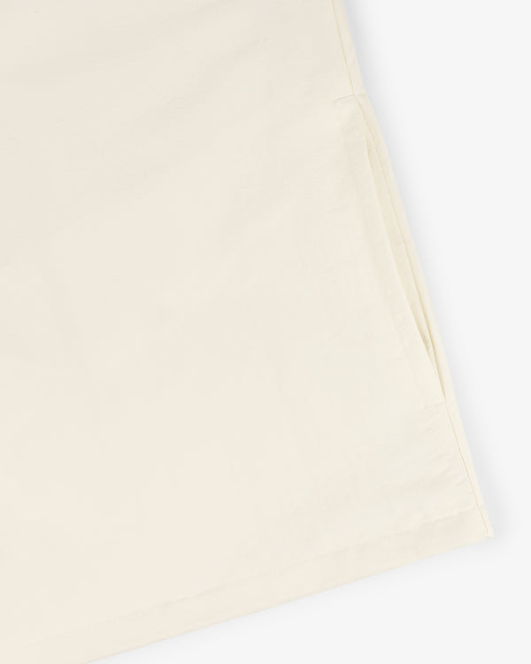 Close-up of Crest Nylon Half-Zip Pullover in light beige, highlighting the side pocket and hem on a white background.