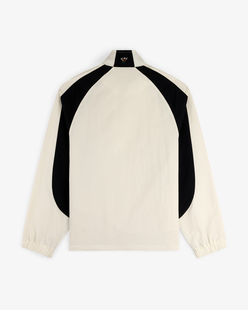 Crest Nylon Half-Zip Pullover in beige with black curved back panels and elastic cuffs, shown on white background.