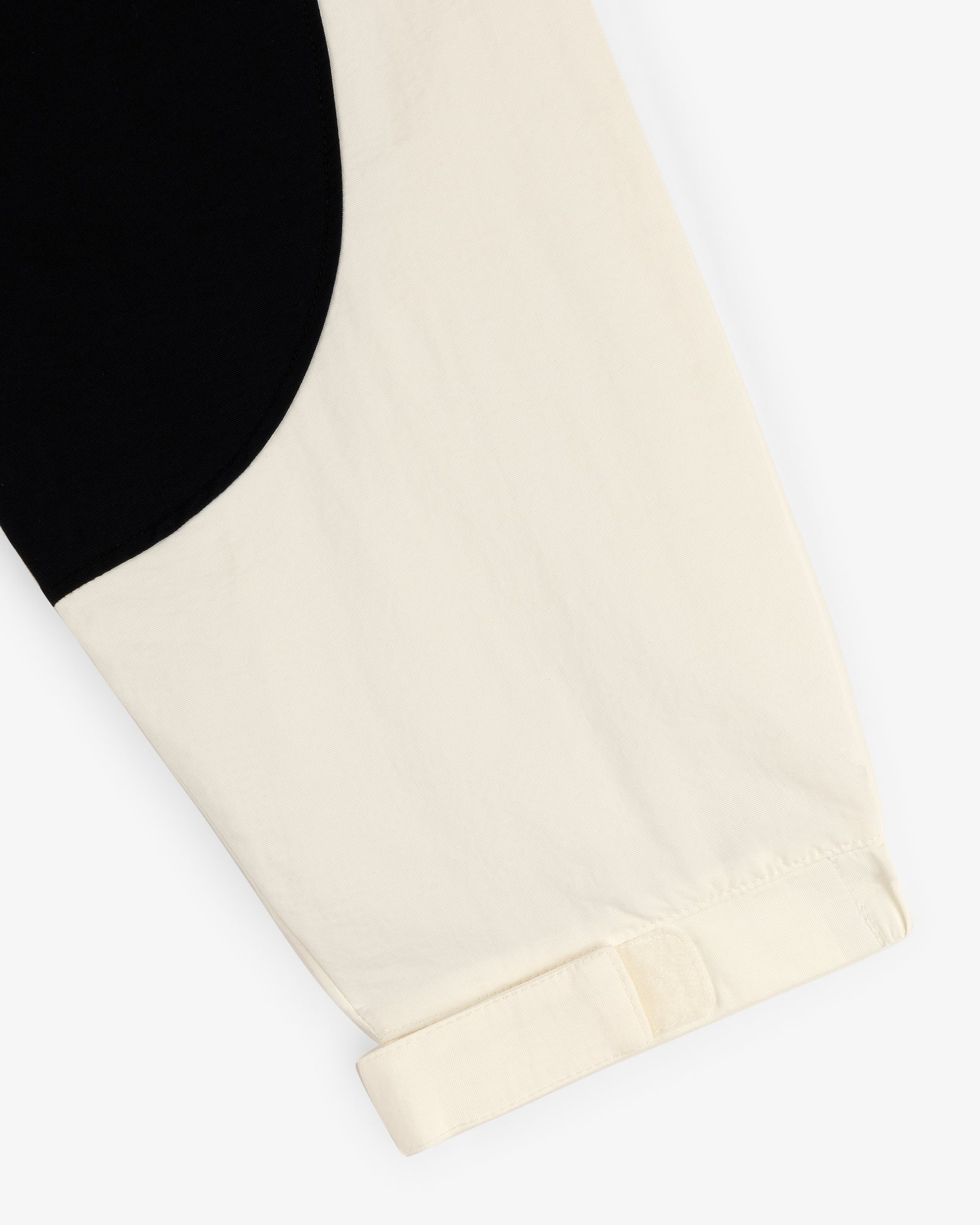 Close-up of the Crest Nylon Half-Zip Pullover’s cream sleeve with black curved detail and a turned-up cuff.