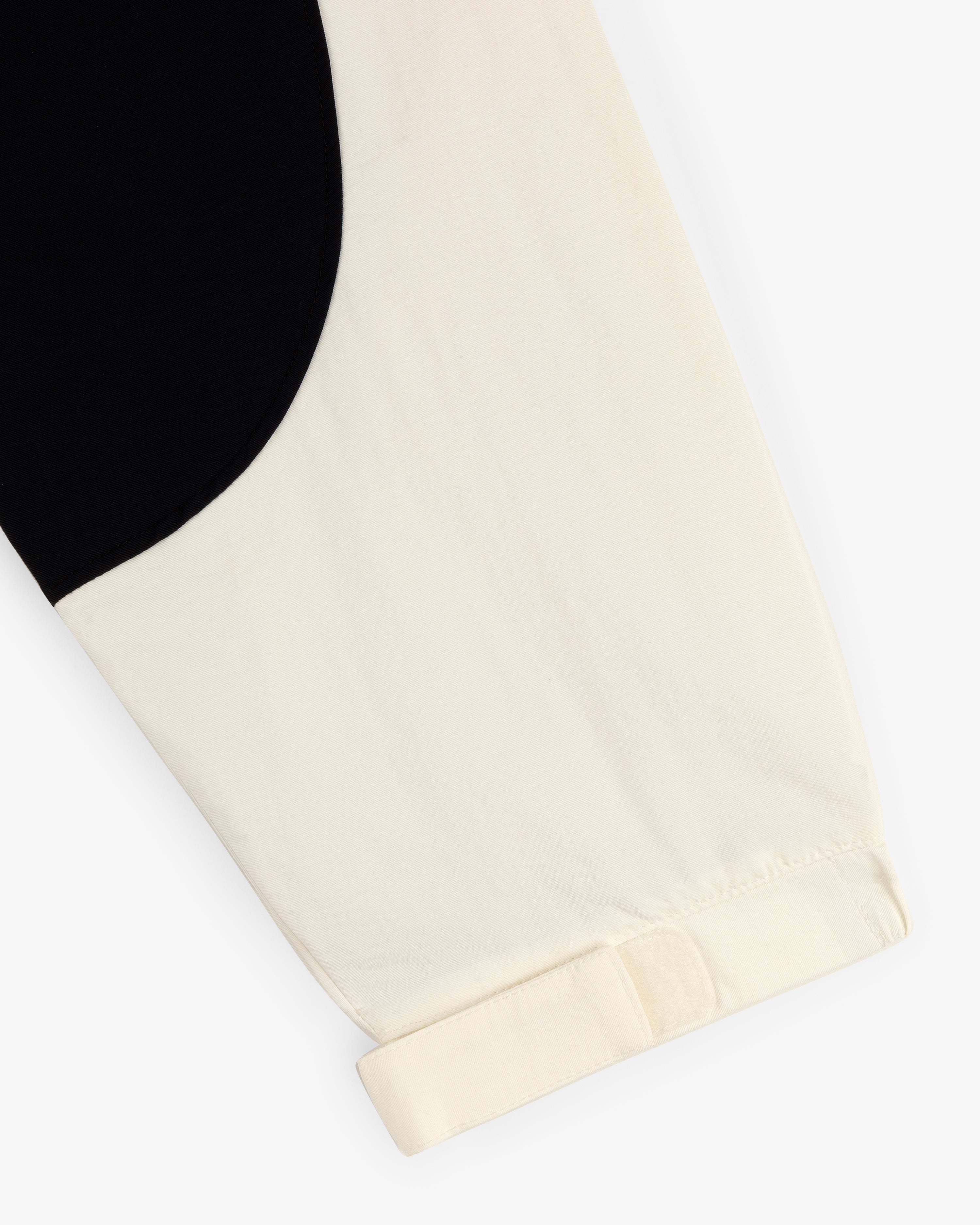 Close-up of the Crest Nylon Half-Zip Pullover’s cream sleeve with black curved detail and a turned-up cuff.