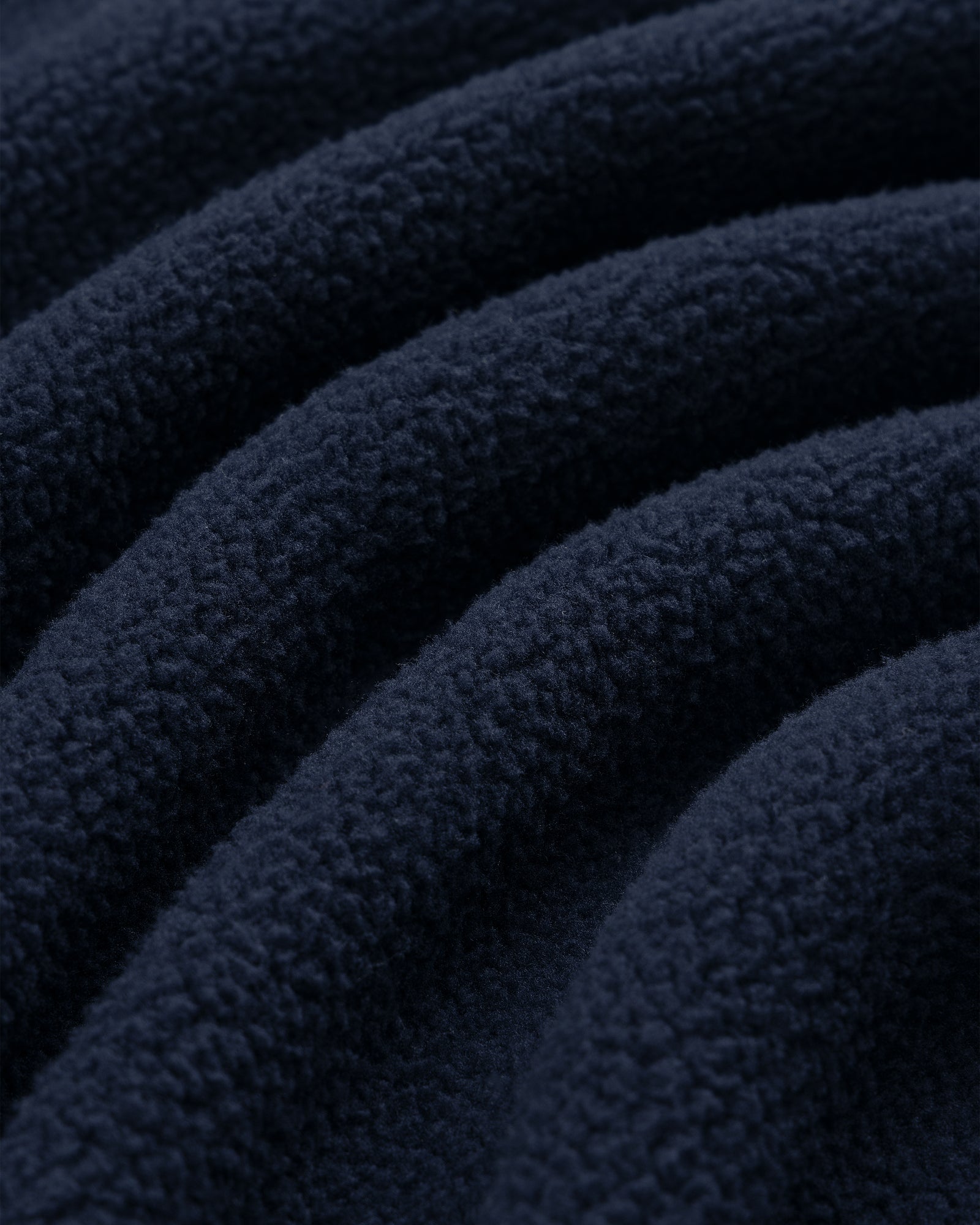 Close-up of Crest Quarter-Zip Fleece Pullover in dark blue, showing soft, wavy textured ridges on the fabric.