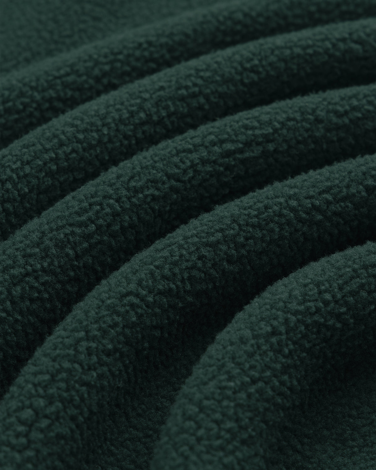 Close-up of Crest Quarter-Zip Fleece Pullover in dark green, highlighting its soft, textured surface and gentle folds.