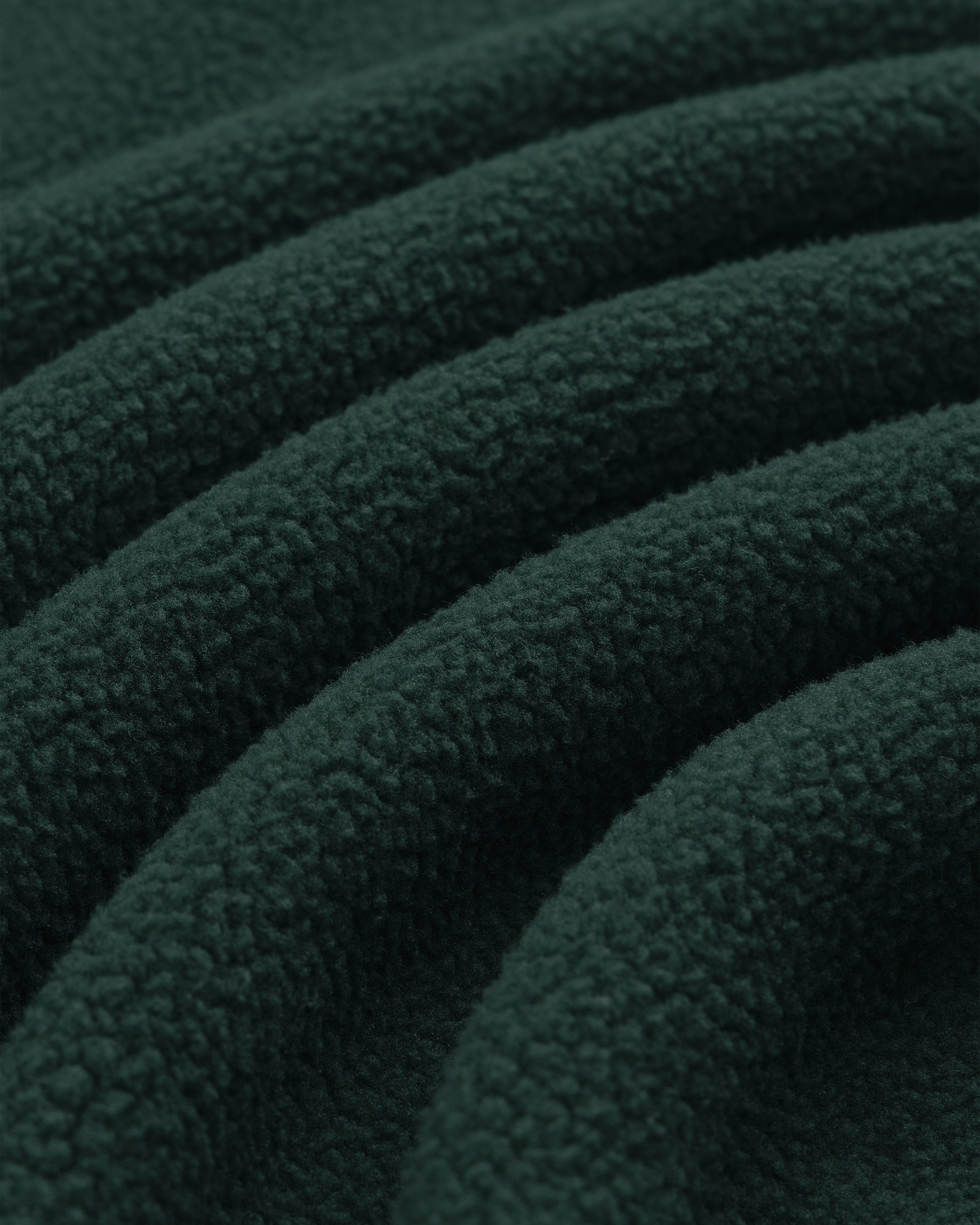 Close-up of Crest Quarter-Zip Fleece Pullover in dark green, highlighting its soft, textured surface and gentle folds.