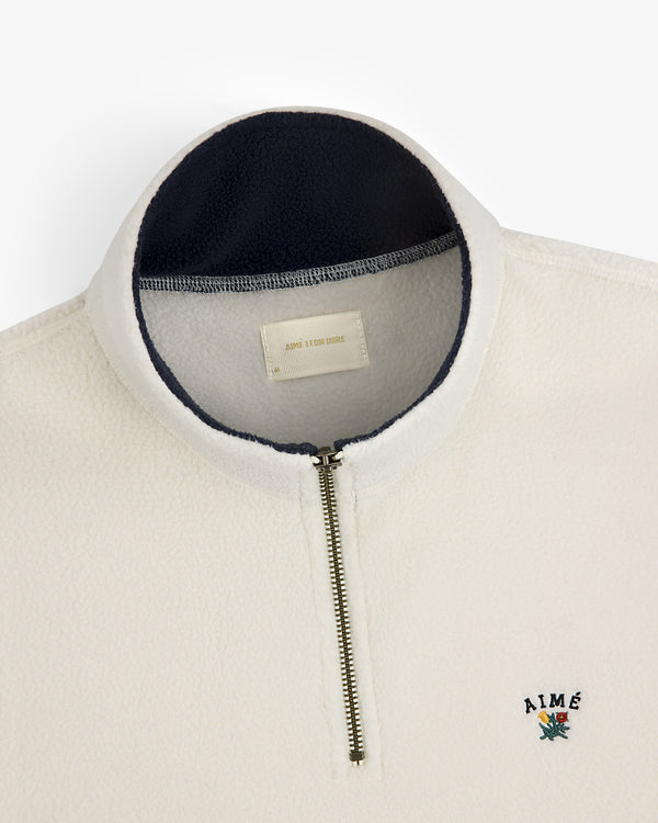 Crest Quarter-Zip Fleece Pullover in white with navy collar lining and embroidered AIMÉ logo on the chest.