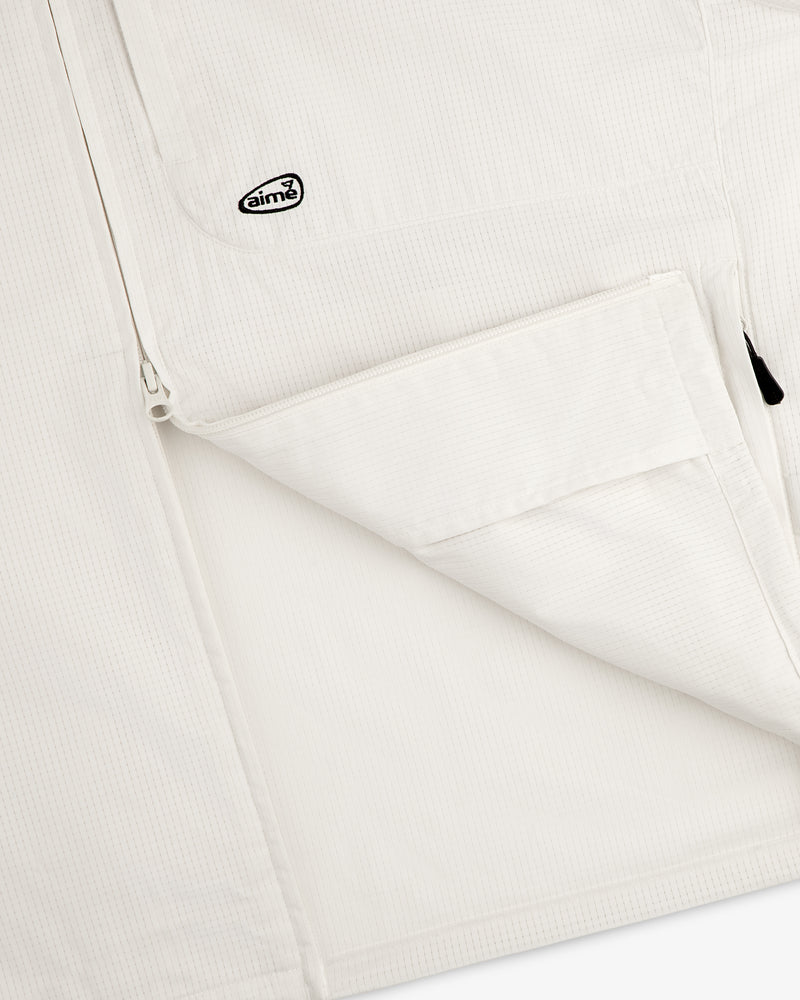 Close-up of the ALD Golf Lightweight Tips Windbreaker, featuring a zip pocket and small Aimé logo patch near the zipper.