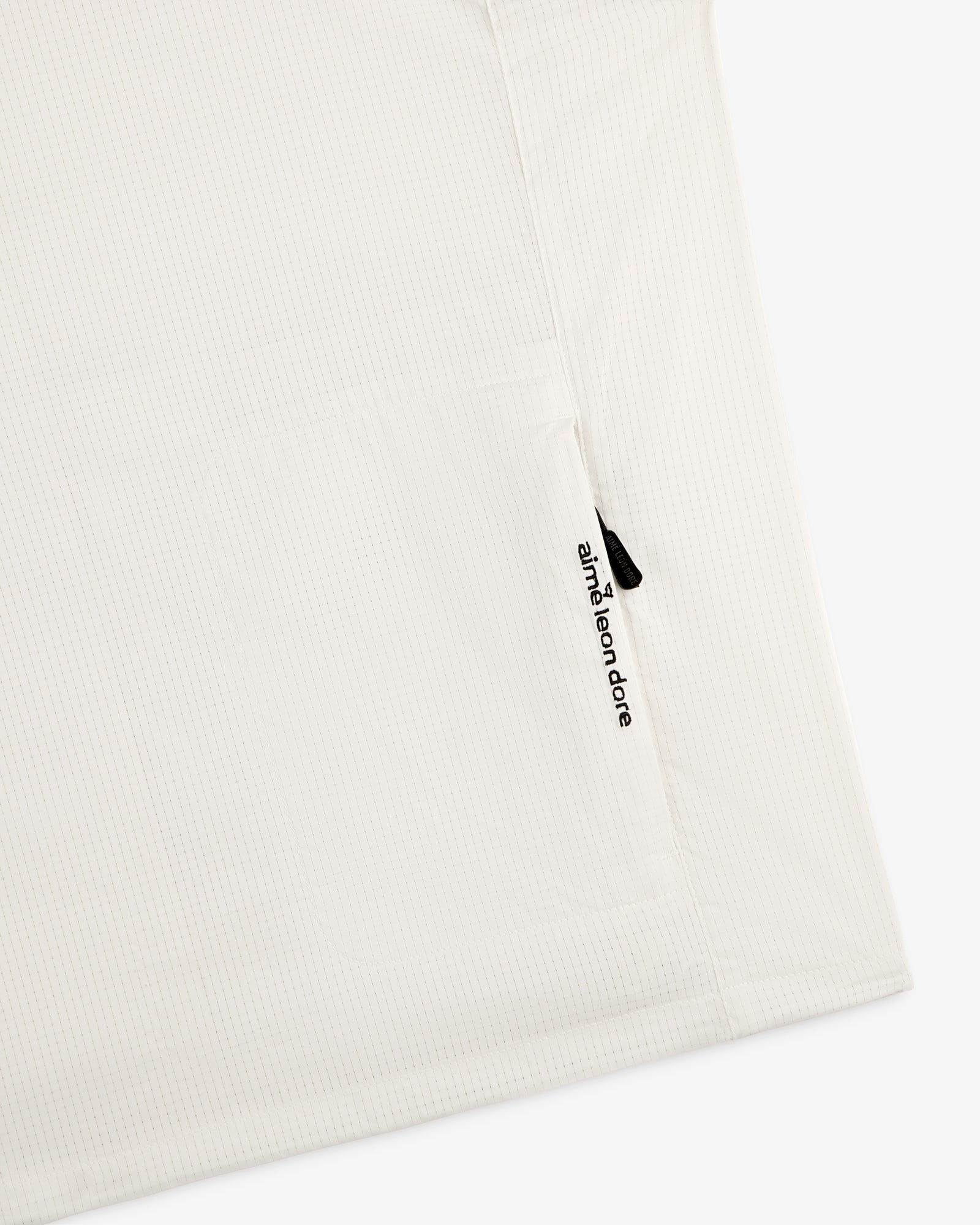 White textured ALD Golf Lightweight Tips Windbreaker with a small vertical zipper pocket and aimé leon dore text.