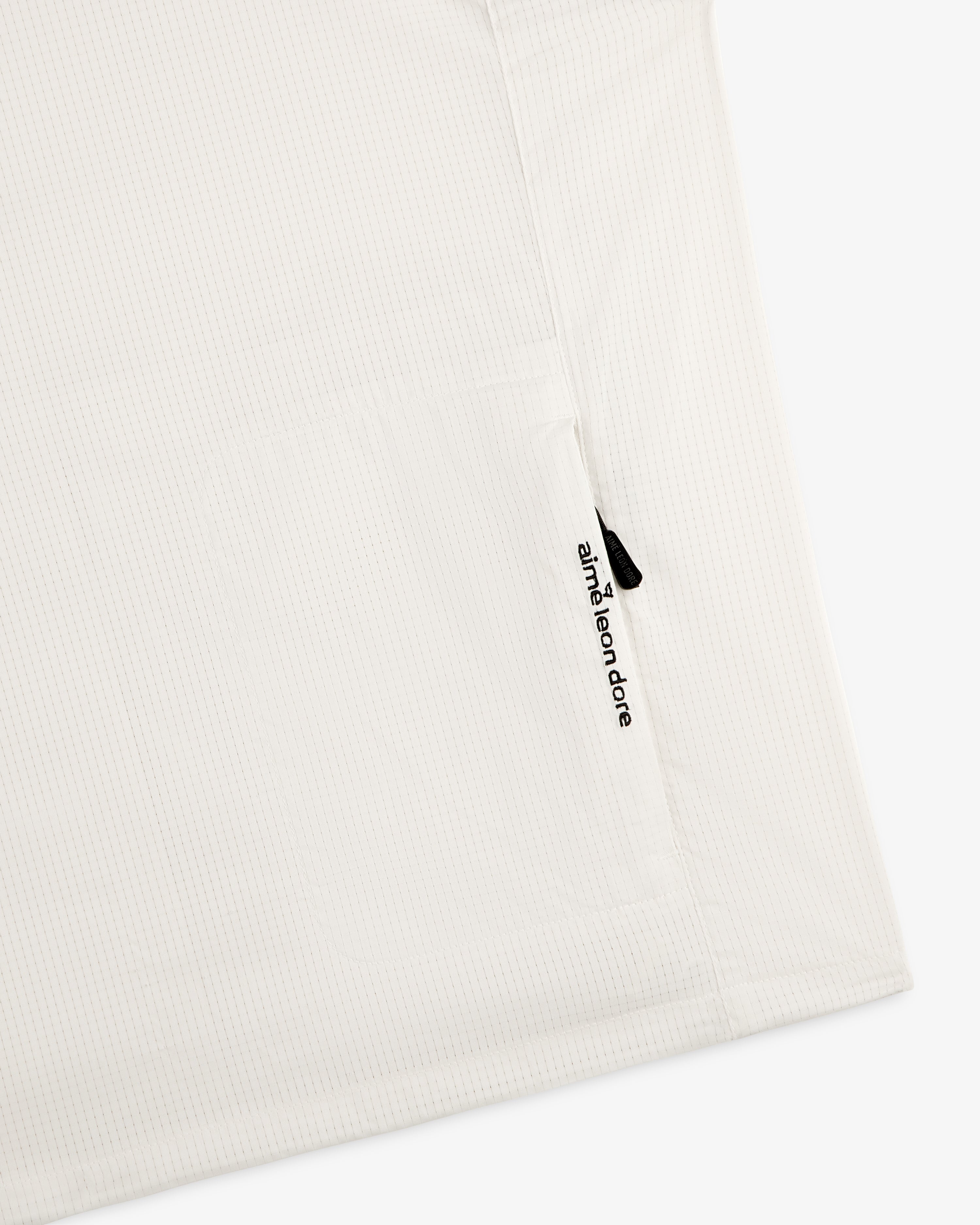 White textured ALD Golf Lightweight Tips Windbreaker with a small vertical zipper pocket and aimé leon dore text.