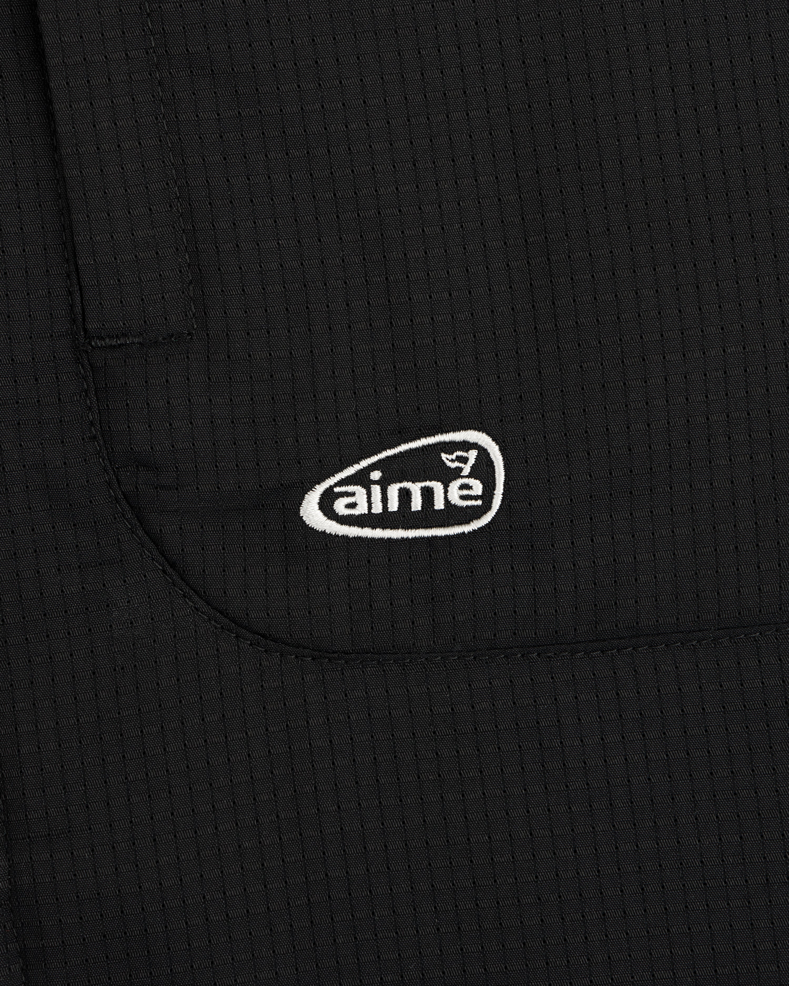 Black textured fabric ALD Golf Lightweight Tips Windbreaker with small white aime logo embroidered on pocket.