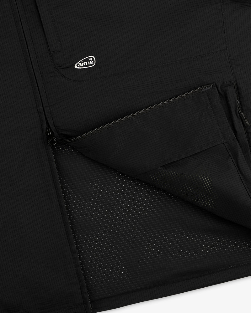 Close-up of the ALD Golf Lightweight Tips Windbreaker’s black pocket, half-zipped, with logo patch above.