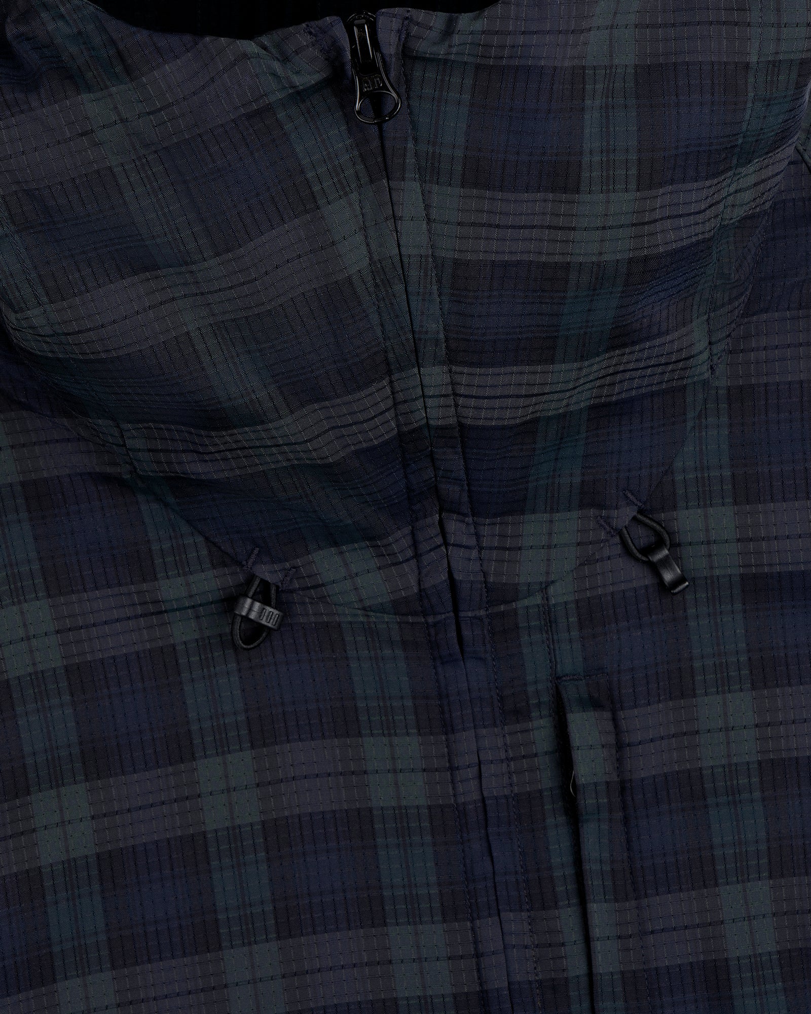 Close-up of the ALD Golf Lightweight Tips Windbreaker featuring a plaid pattern, zipper, and two black toggle adjusters.
