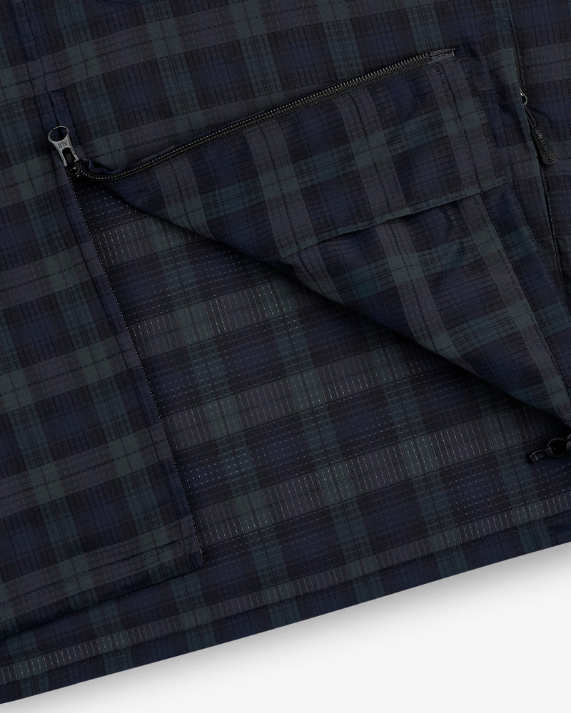 Close-up of the ALD Golf Lightweight Tips Windbreaker in navy and green plaid with a zippered pocket and visible stitching.