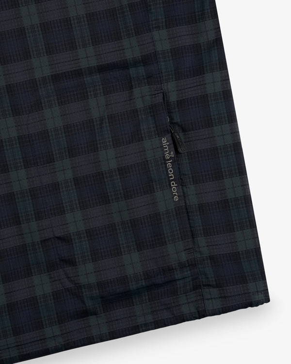 Close-up of ALD Golf Lightweight Tips Windbreaker in dark green and navy plaid with a small label near the seam.