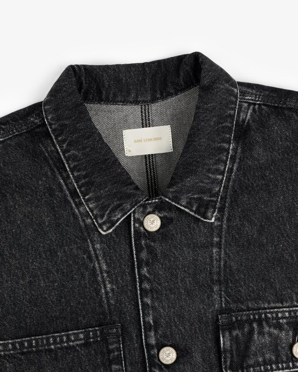 Close-up of a Denim Trucker Jacket in black with beige buttons and a label inside the collar.