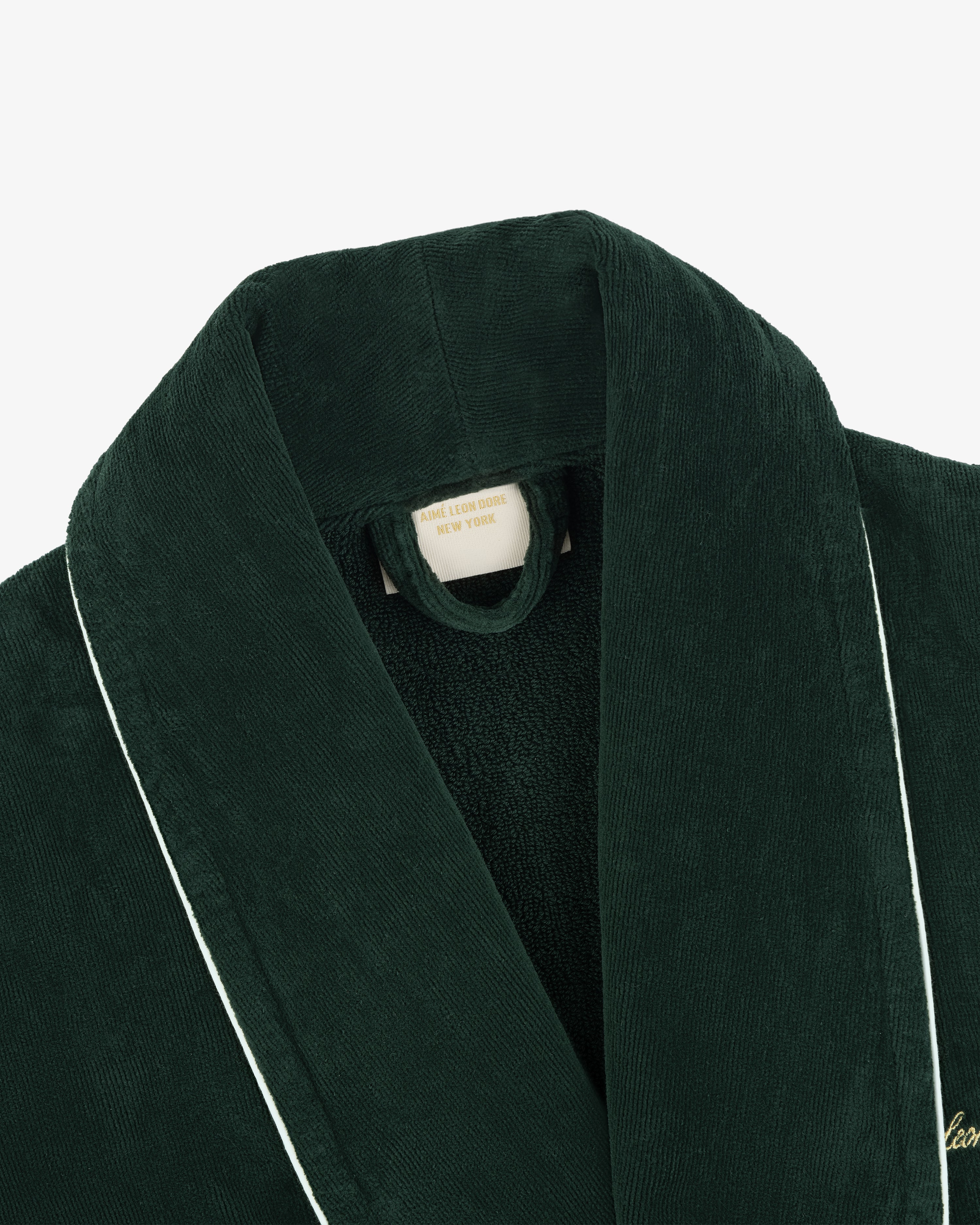 Close-up of a dark green corduroy Mulberry Robe with white piping and a label reading ASCOT LODGE ROBE, NEW YORK.