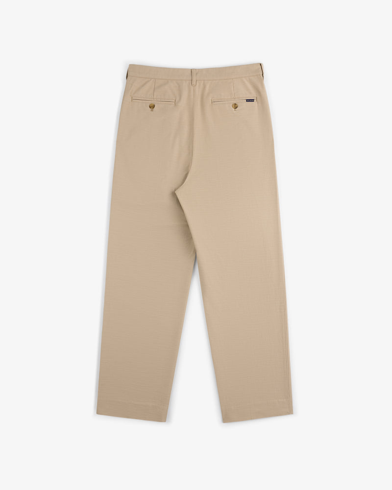 Double Pleated Pant in beige, shown from the back with two buttoned pockets and straight legs on a white background.