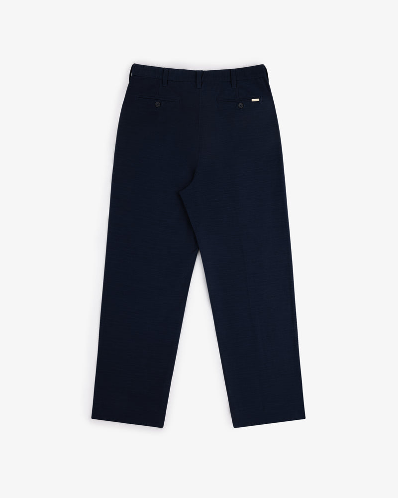 Back view of Double Pleated Pant in dark navy with two back pockets and belt loops, laid flat on white background.