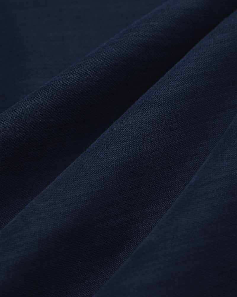 Close-up of Double Pleated Pant in dark blue, showing visible weave texture and soft diagonal folds.
