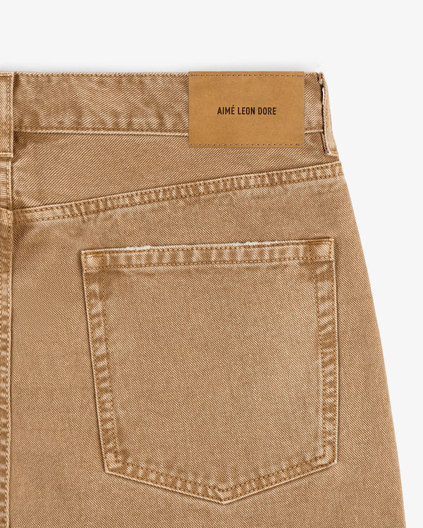Close-up of Relaxed Fit 5-Pocket Denim Pant's tan back pocket with AIMÉ LEON DORE leather patch above it.