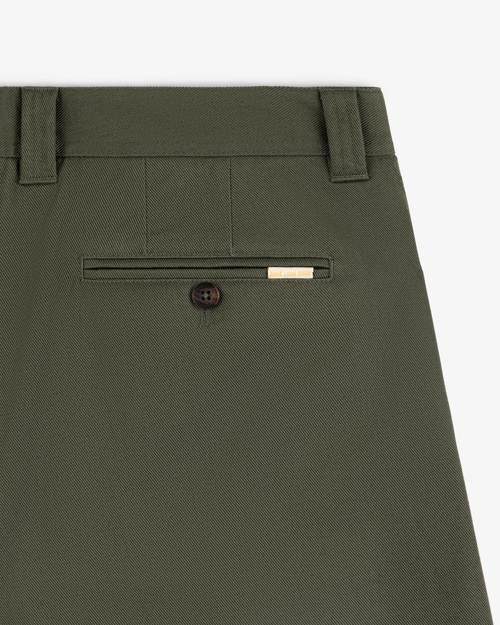 Close-up of Officer Pant in olive green showing a back pocket with button and small gold label above.