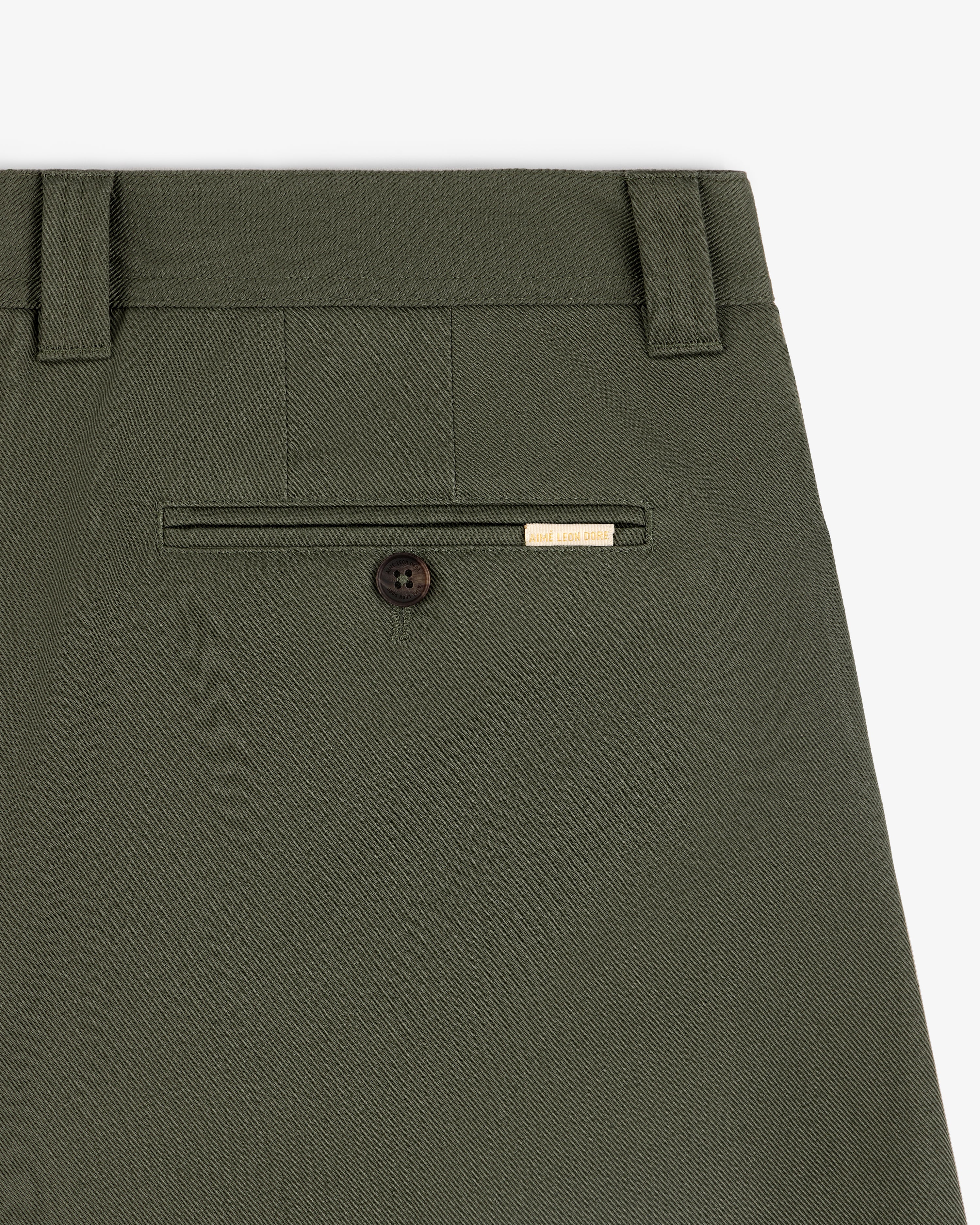 Close-up of Officer Pant in olive green showing a back pocket with button and small gold label above.