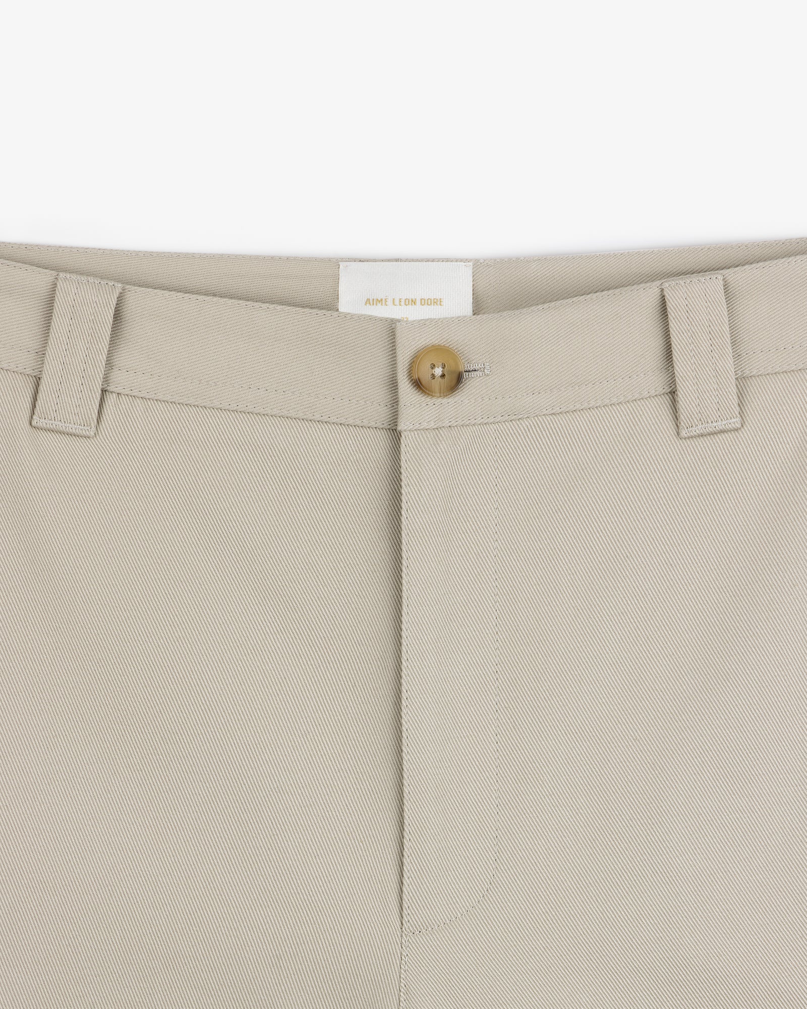 Close-up of Officer Pant in beige, featuring a button closure, belt loops, and prominent waistband stitching.
