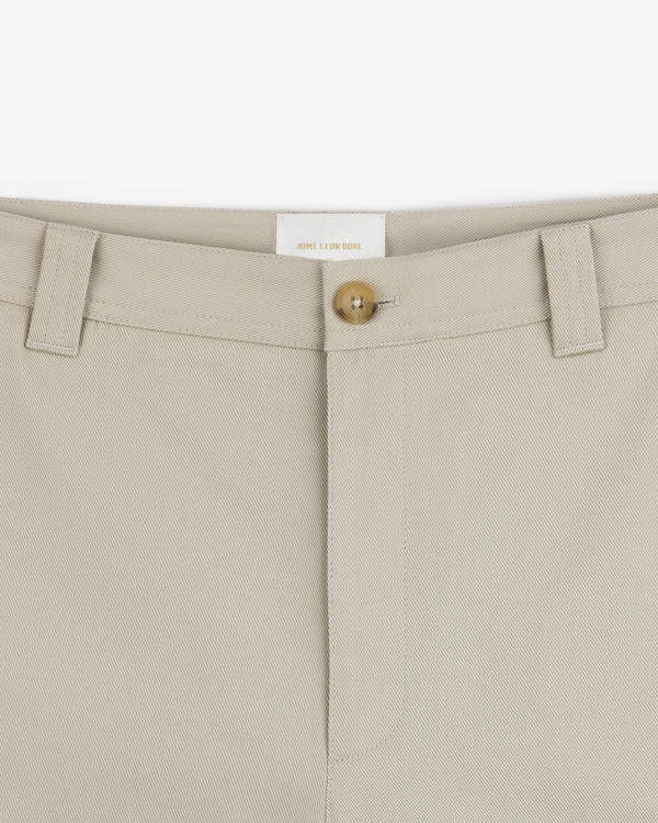 Close-up of Officer Pant in beige, featuring a button closure, belt loops, and prominent waistband stitching.