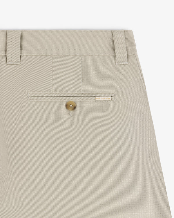 Close-up of Officer Pant in beige showing a back welt pocket with button and a small beige label above it.