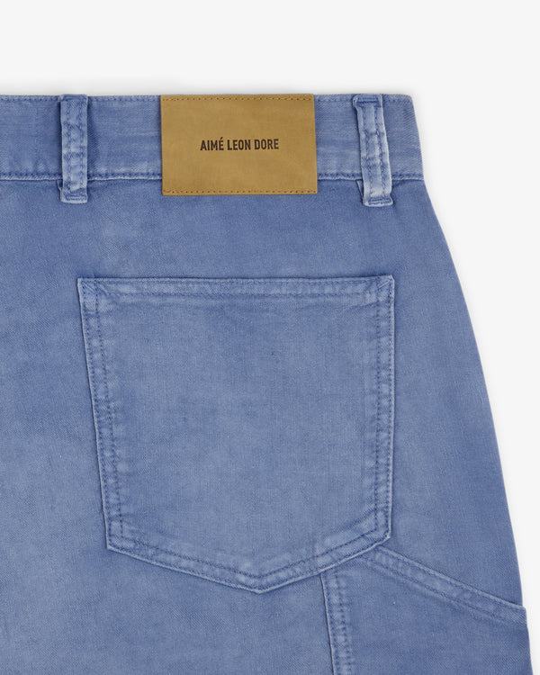 Close-up of light blue Linen Blend Carpenter Pant with back pocket and tan leather AIMÉ LEON DORE patch above it.