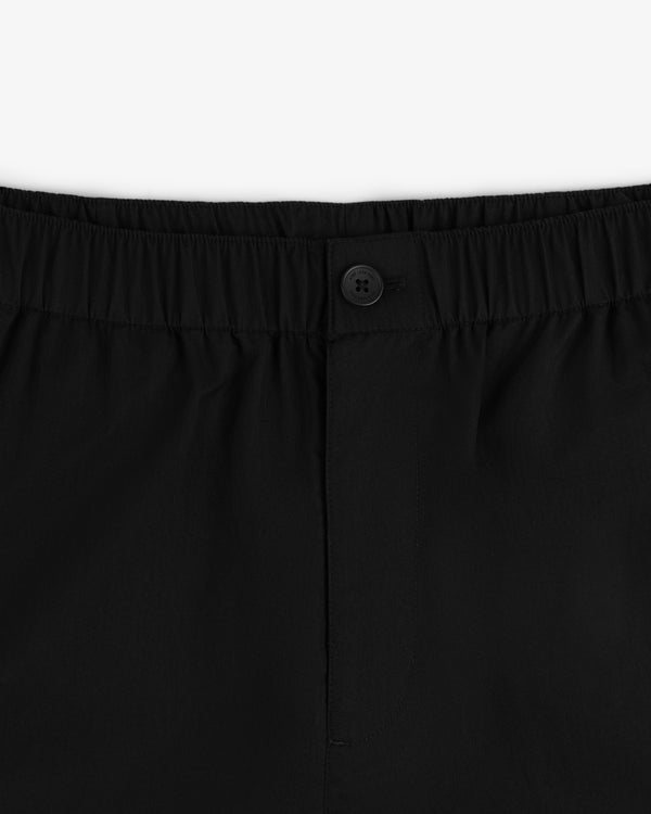 Close-up of the waistband of Relaxed Cotton Trouser in black with an elastic top and a single black button at the center.