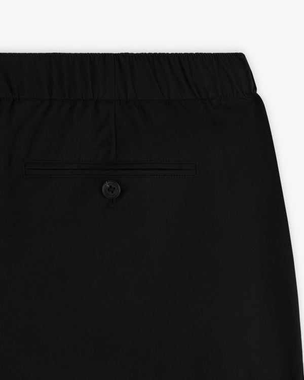 Close-up of Relaxed Cotton Trouser in black with an elastic waistband and a buttoned back pocket.