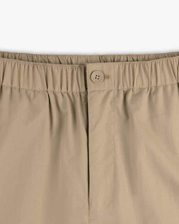 Close-up of Relaxed Cotton Trouser in beige, featuring an elastic waistband, button closure, and front stitched seam.