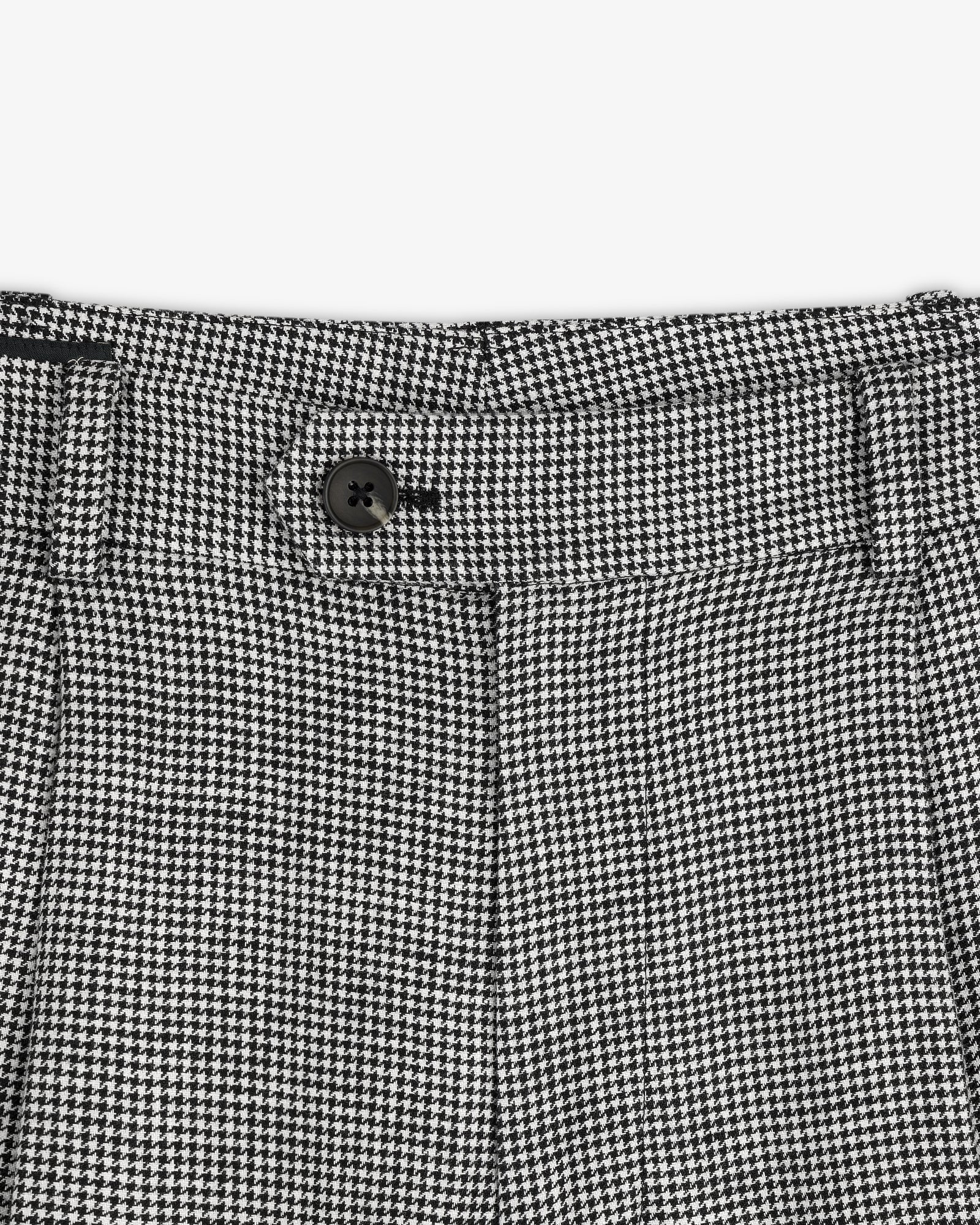 Close-up of the waistband on Houndstooth Pleated Trouser featuring a black button and belt loops.