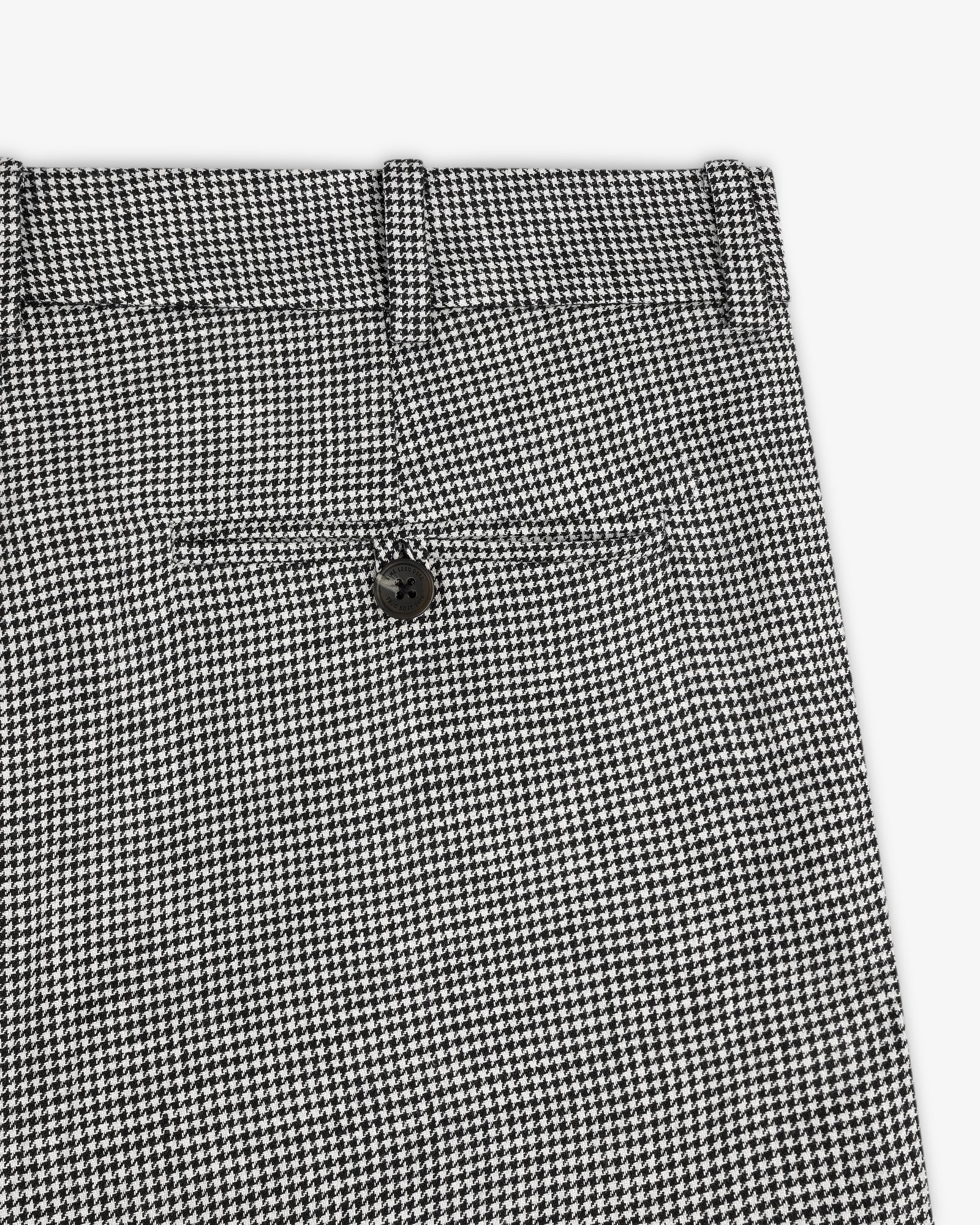 Close-up of Houndstooth Pleated Trouser in black and white, featuring a back pocket and black button.